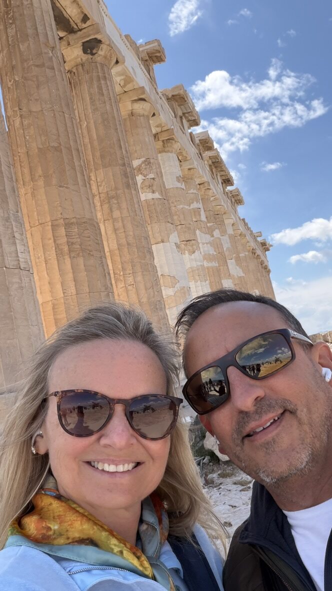 She-Stache and He-Stache taking a selfie beneath the columns of the Parthenon
