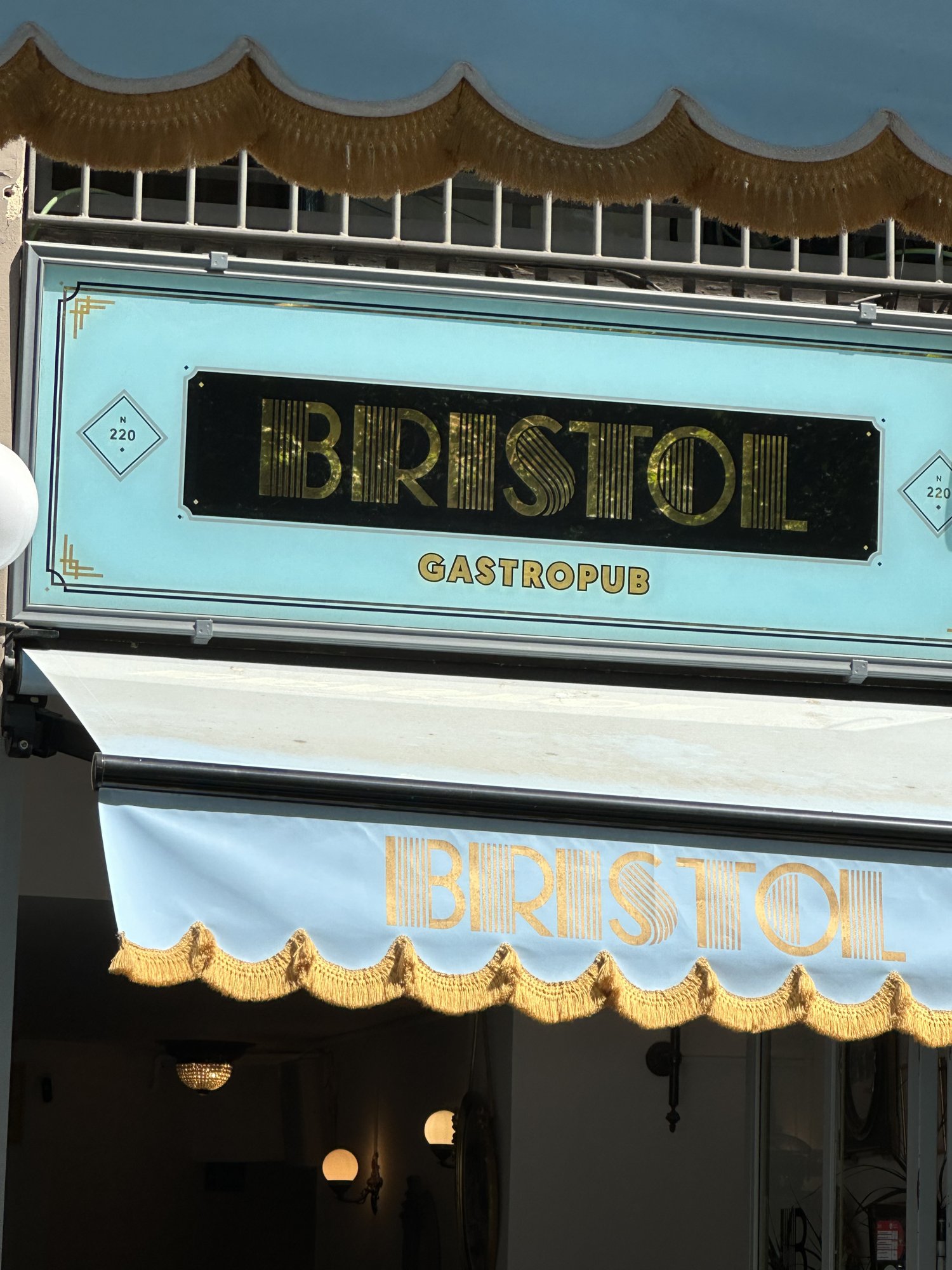 A turquoise and gold storefront sign reading Bristol Gastropub above a striped awning