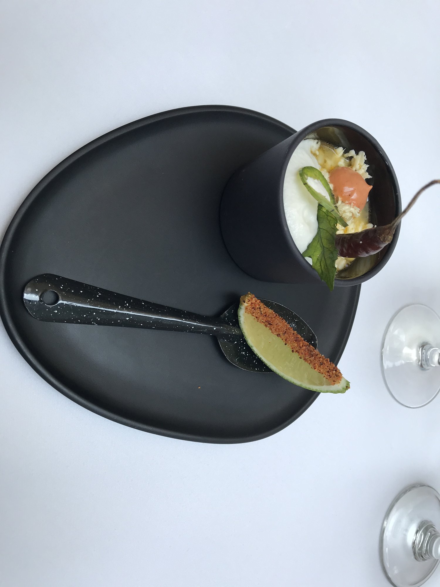 A small bowl and a fig half on a black plate