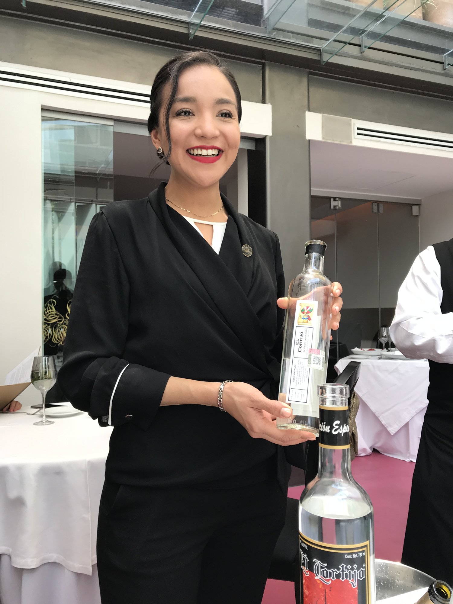 A server presenting a bottle of mezcal in the dining room