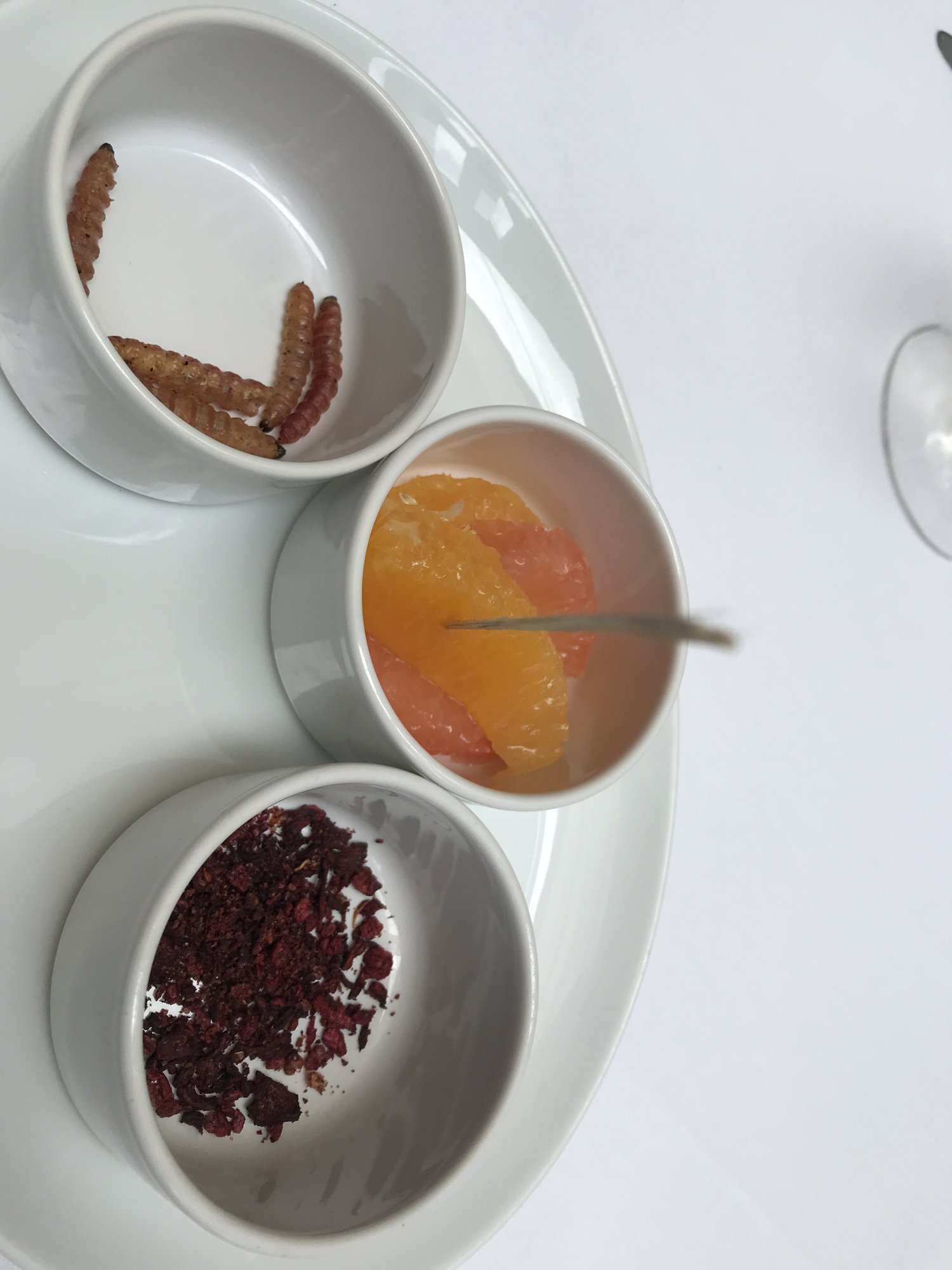 Three small bowls of salts and sauces with toasted grasshoppers