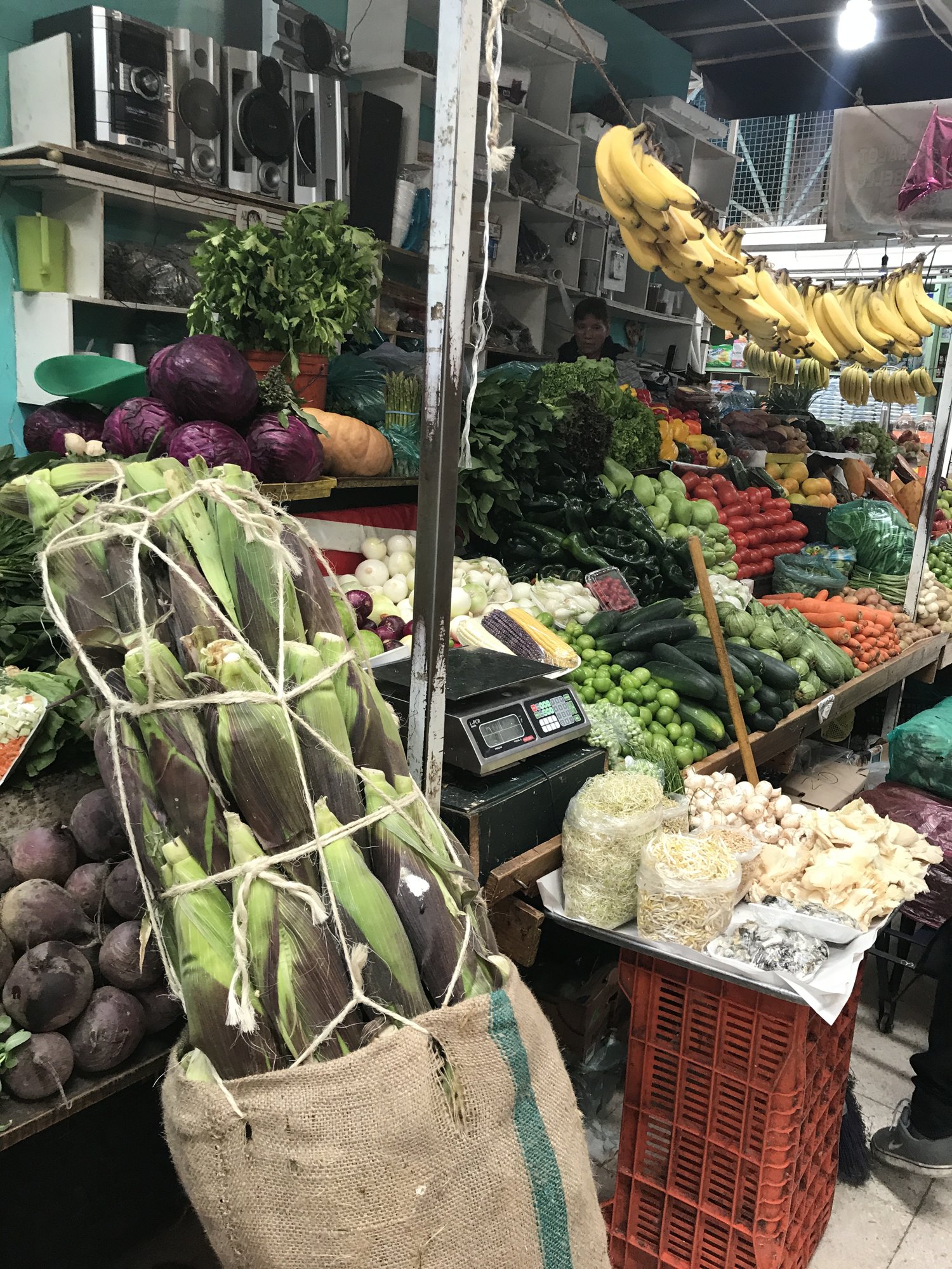 Bundles of dried corn husks and produce at a market stand