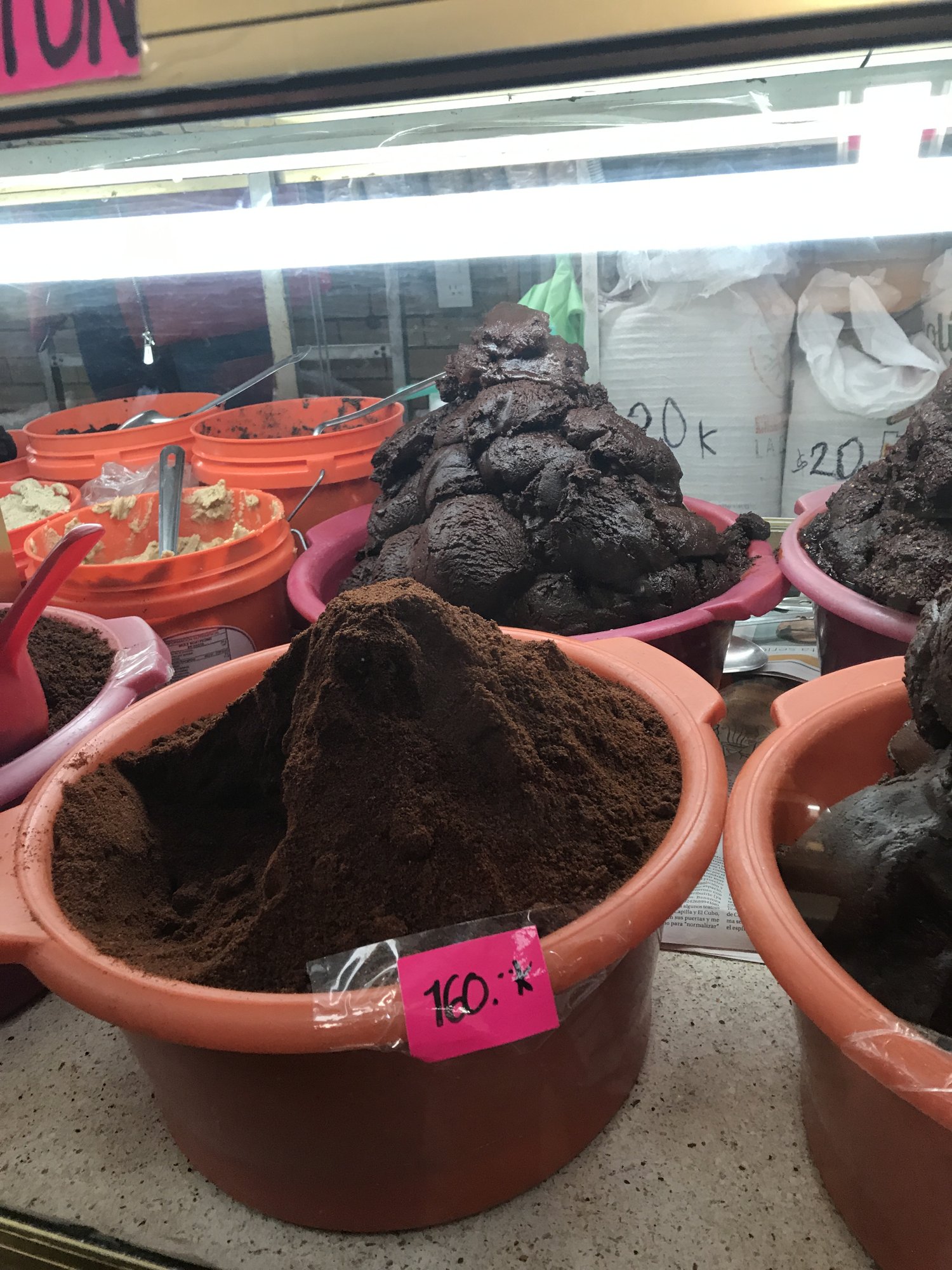 Tubs of dark mole paste and dried chiles at a market stall