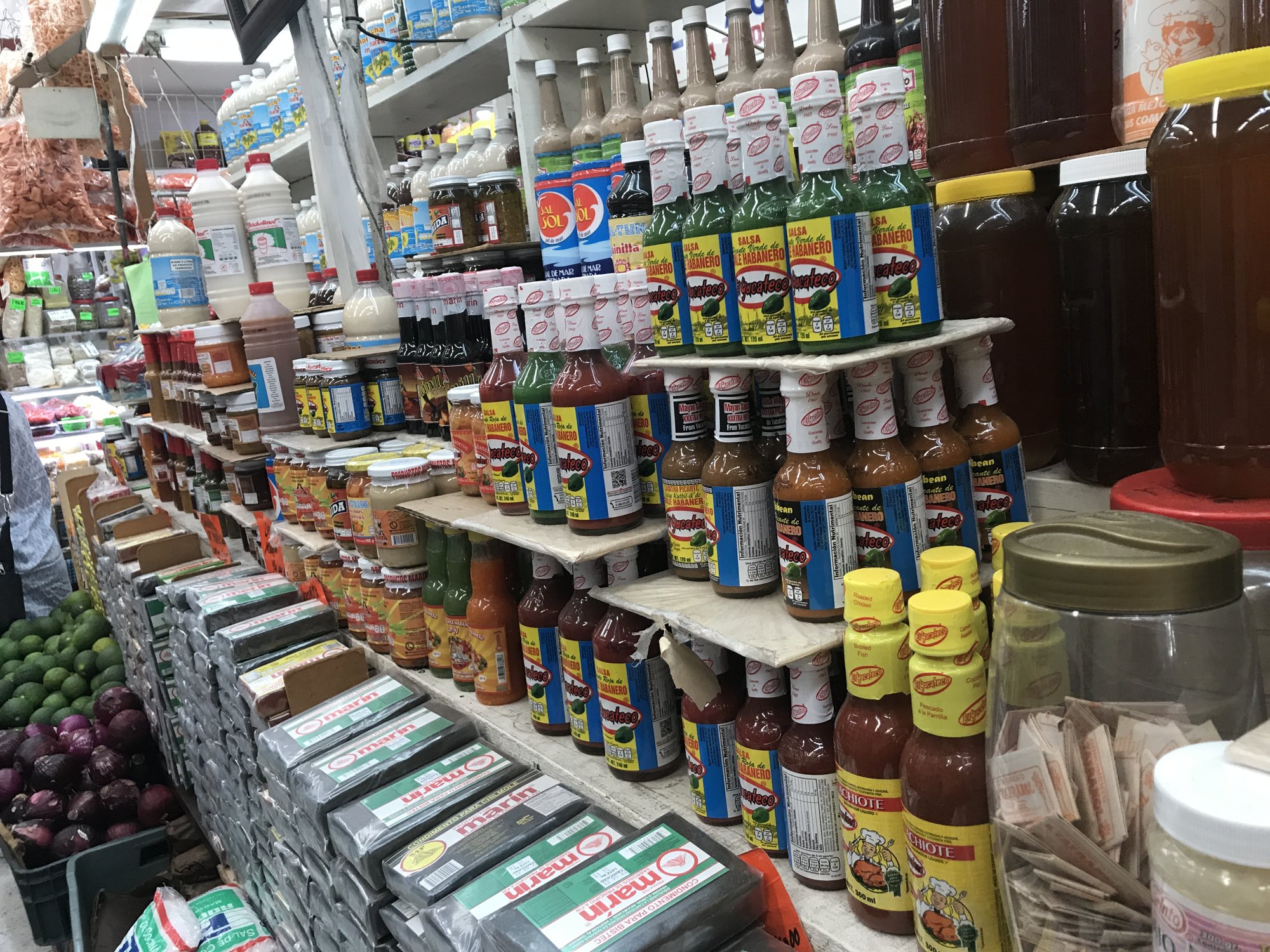 Market shelves stacked high with jars, cans and bottles of sauce