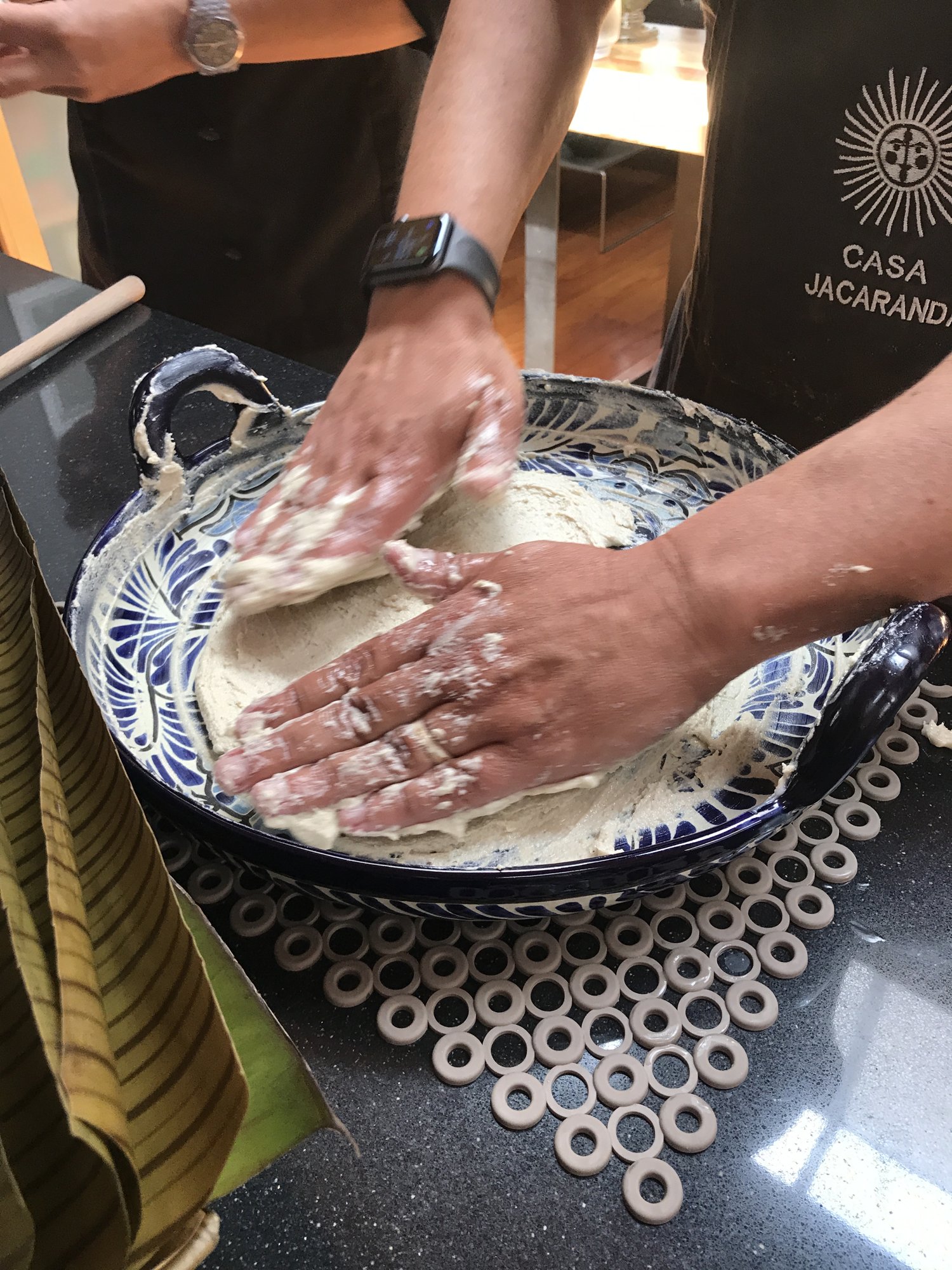 Hands kneading masa in a blue-and-white ceramic bowl