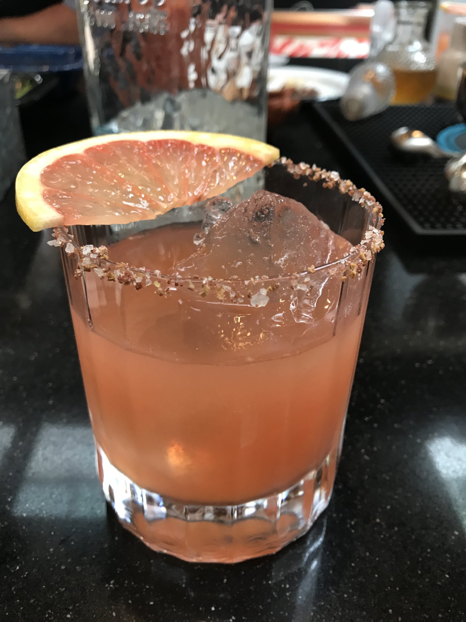 A grapefruit paloma with a salted rim and a grapefruit wheel