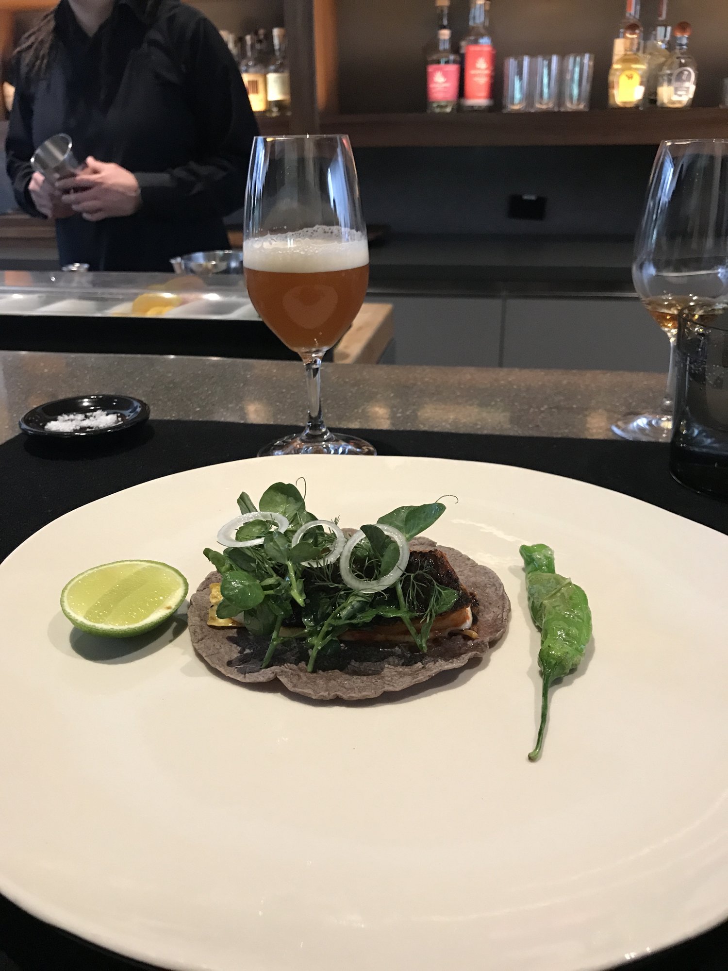 A taco with greens beside a lime wedge and a glass of beer at Pujol&rsquo;s bar