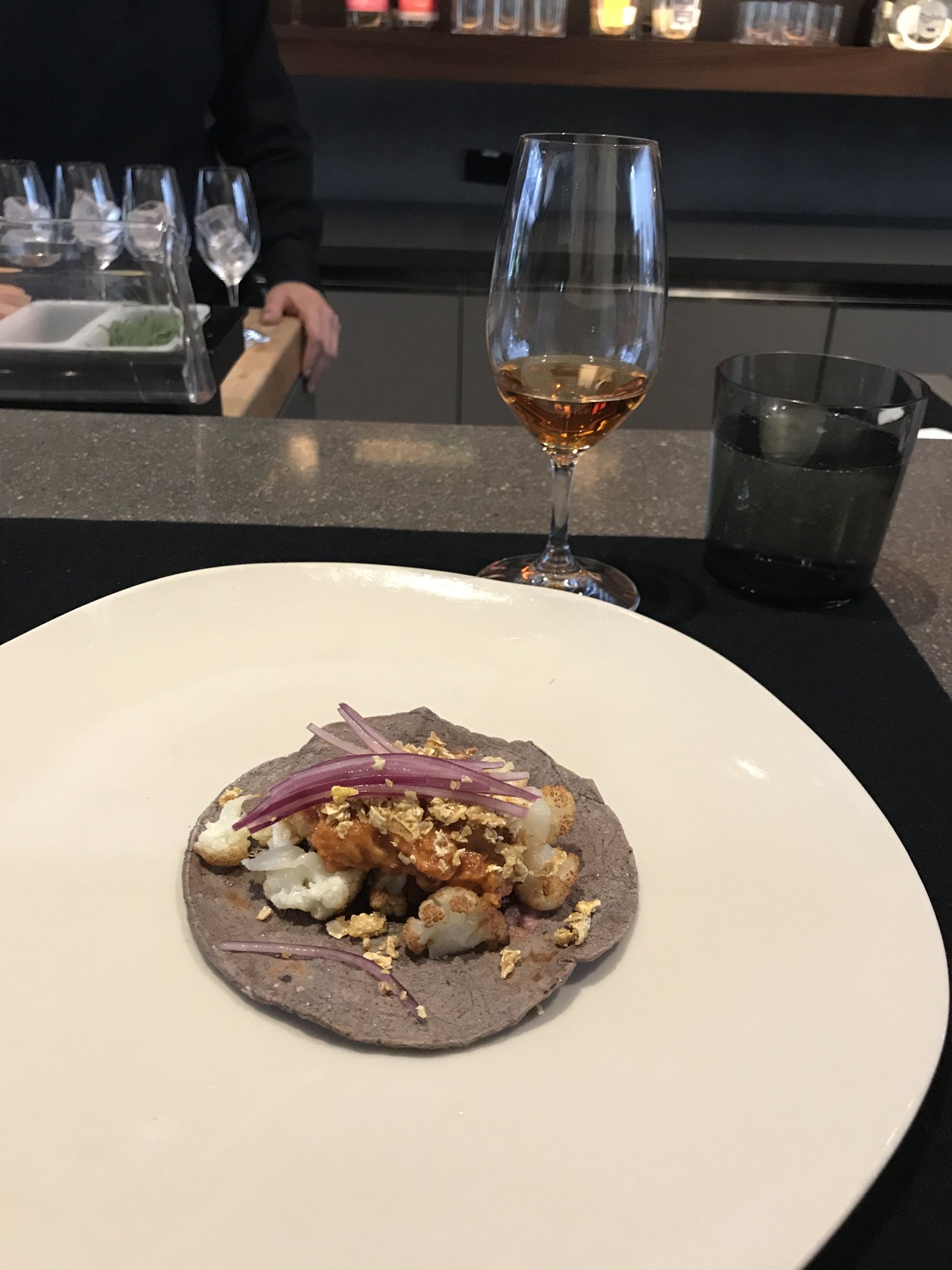 A blue-corn tostada topped with seafood and onion on a white plate