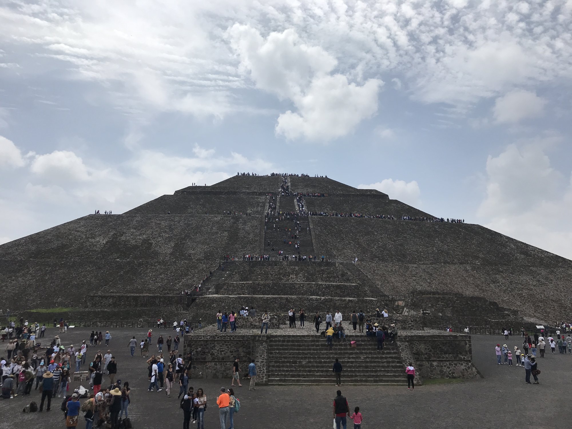 The Pyramid of the Sun under a cloudy sky, with visitors climbing its stairs