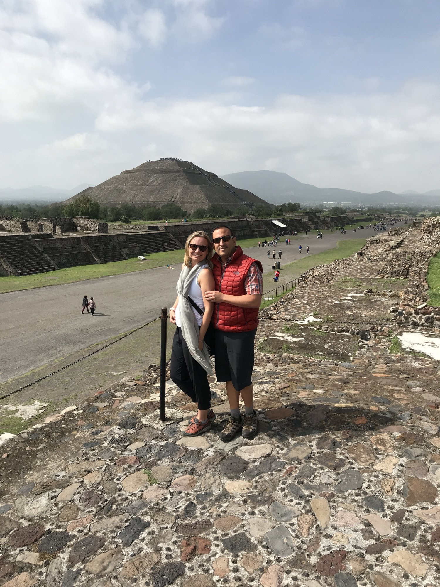 She-Stache and He-Stache standing on a stone wall above the Avenue of the Dead, the Pyramid of the Sun in the distance