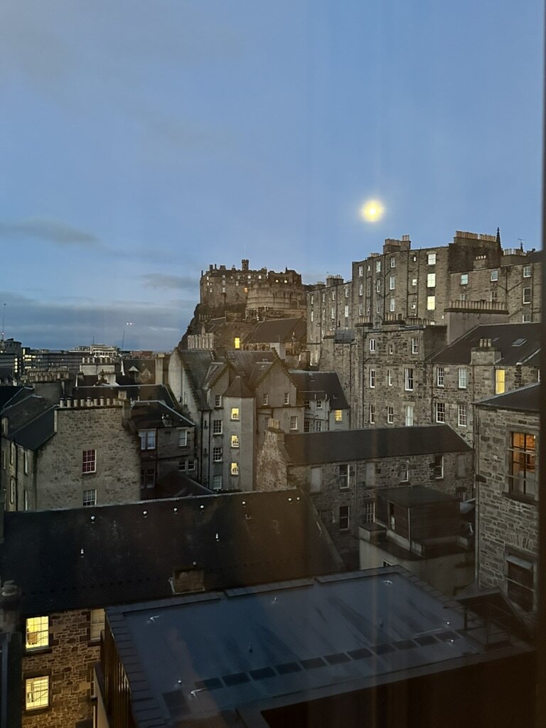 Edinburgh Castle lit up at night beneath a full moon, seen from our hotel room