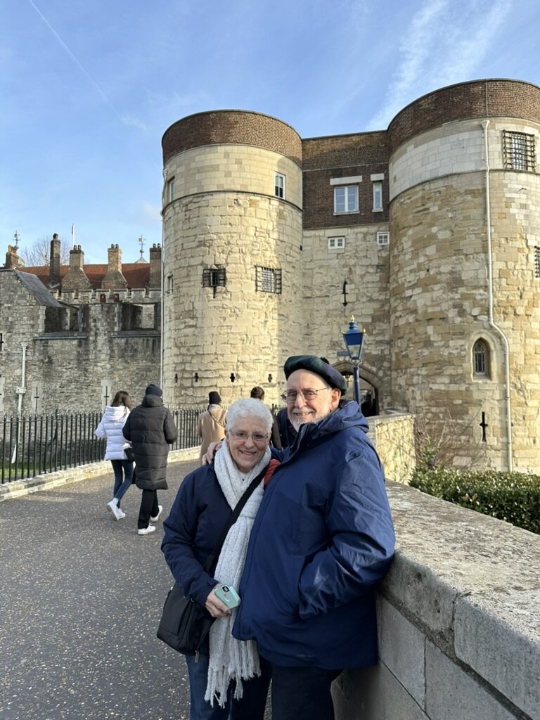 Mom and Dad leaning on a stone wall in front of the Byward Tower entrance at the Tower of London