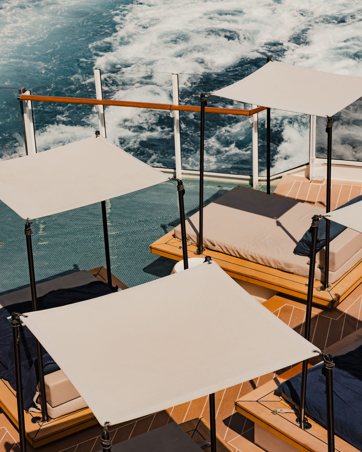 Explora media kit photo of shaded loungers under white canopies at the stern, the ship&rsquo;s white wake churning below