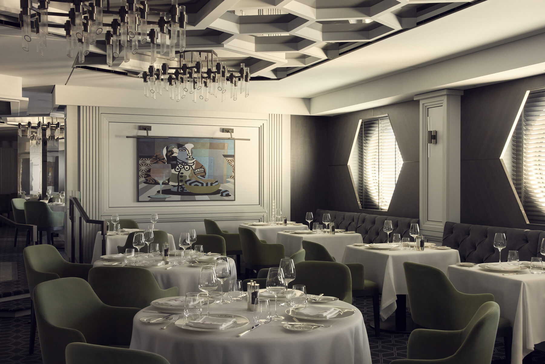 Explora media kit photo of the Fil Rouge dining room, round tables with white linens and a framed artwork on the wall