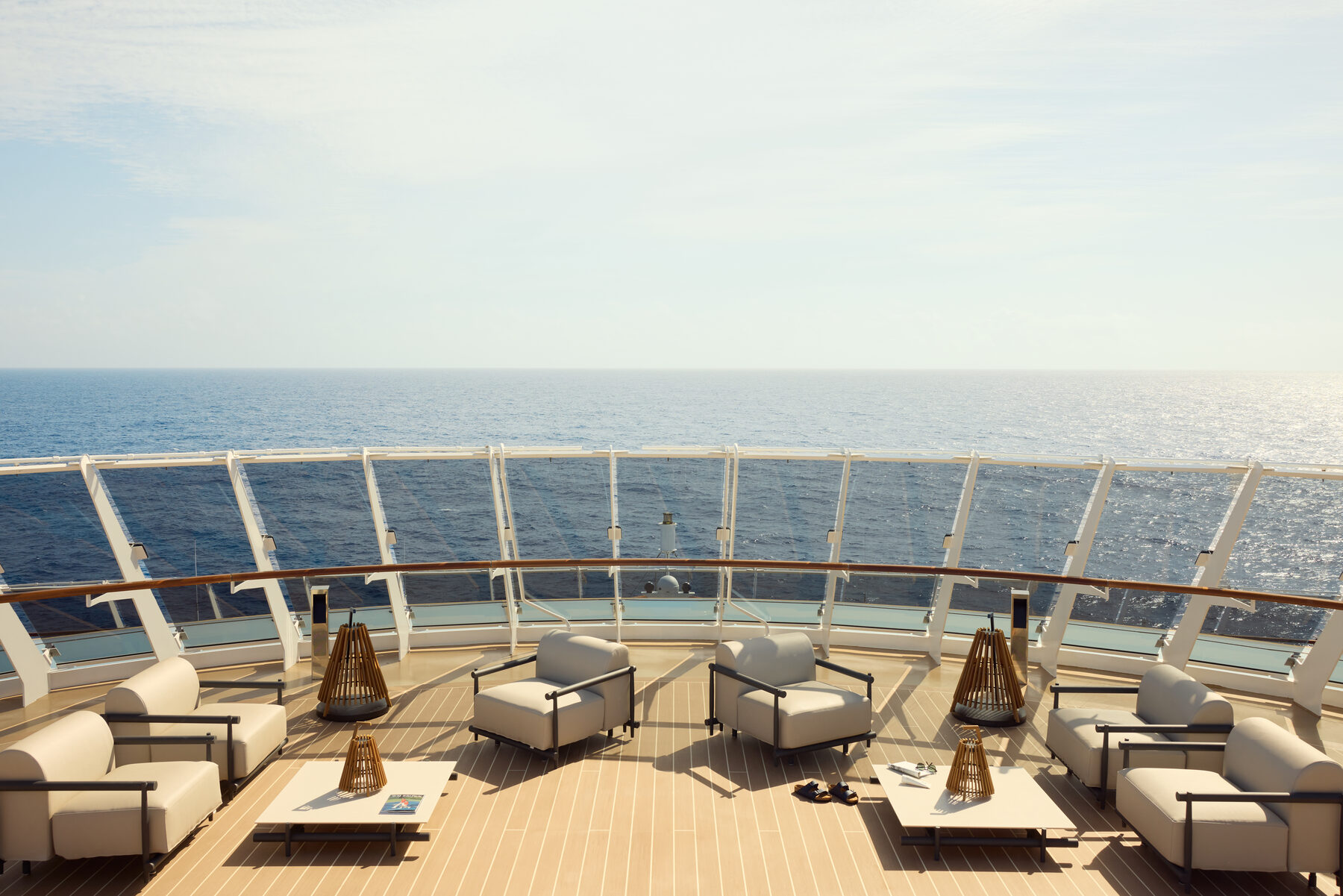 Explora media kit photo of the Helios deck, cream lounge chairs facing the open sea behind a glass railing