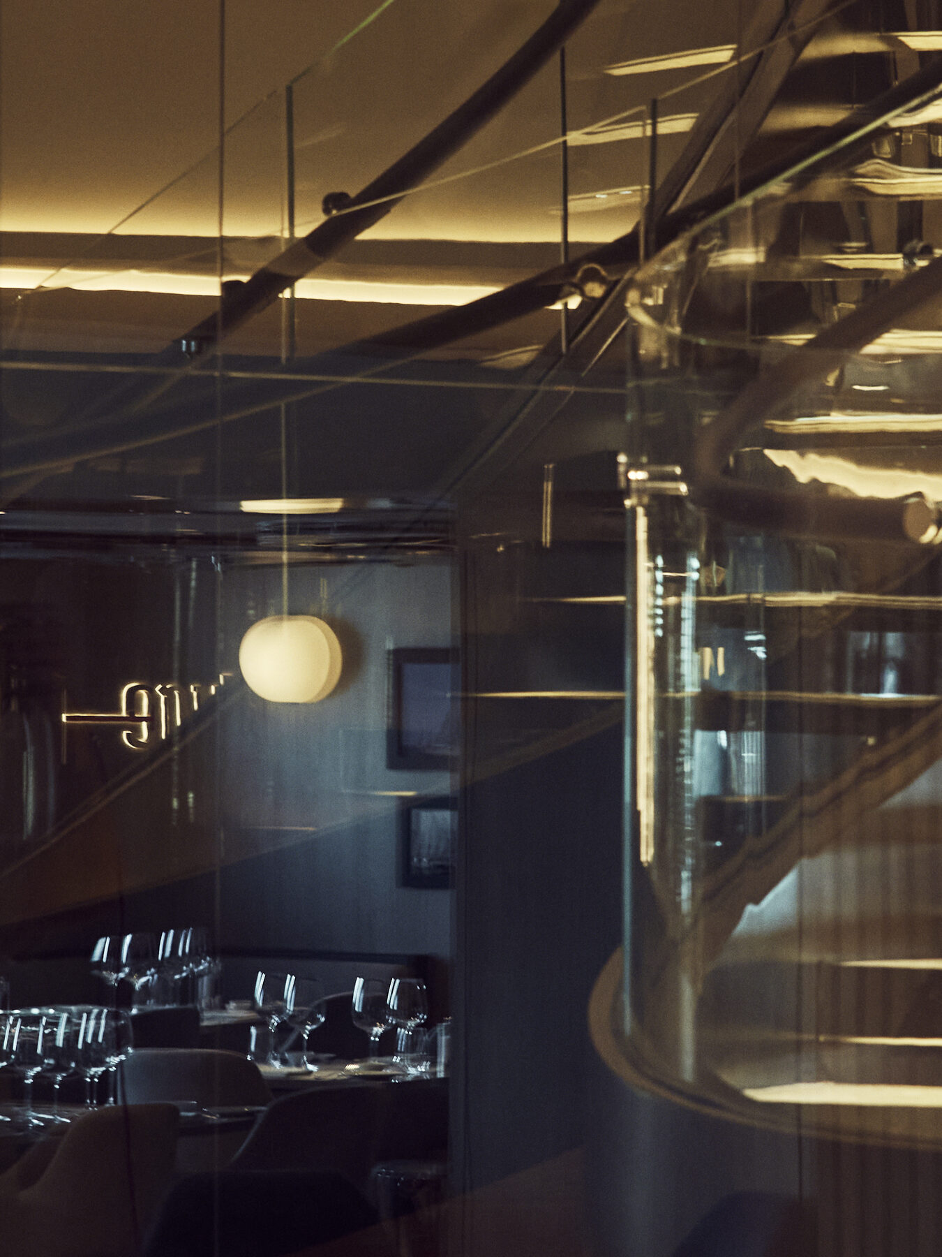 Explora media kit photo of the Med Yacht Club bar, a glass-walled spiral staircase and globe pendant lights