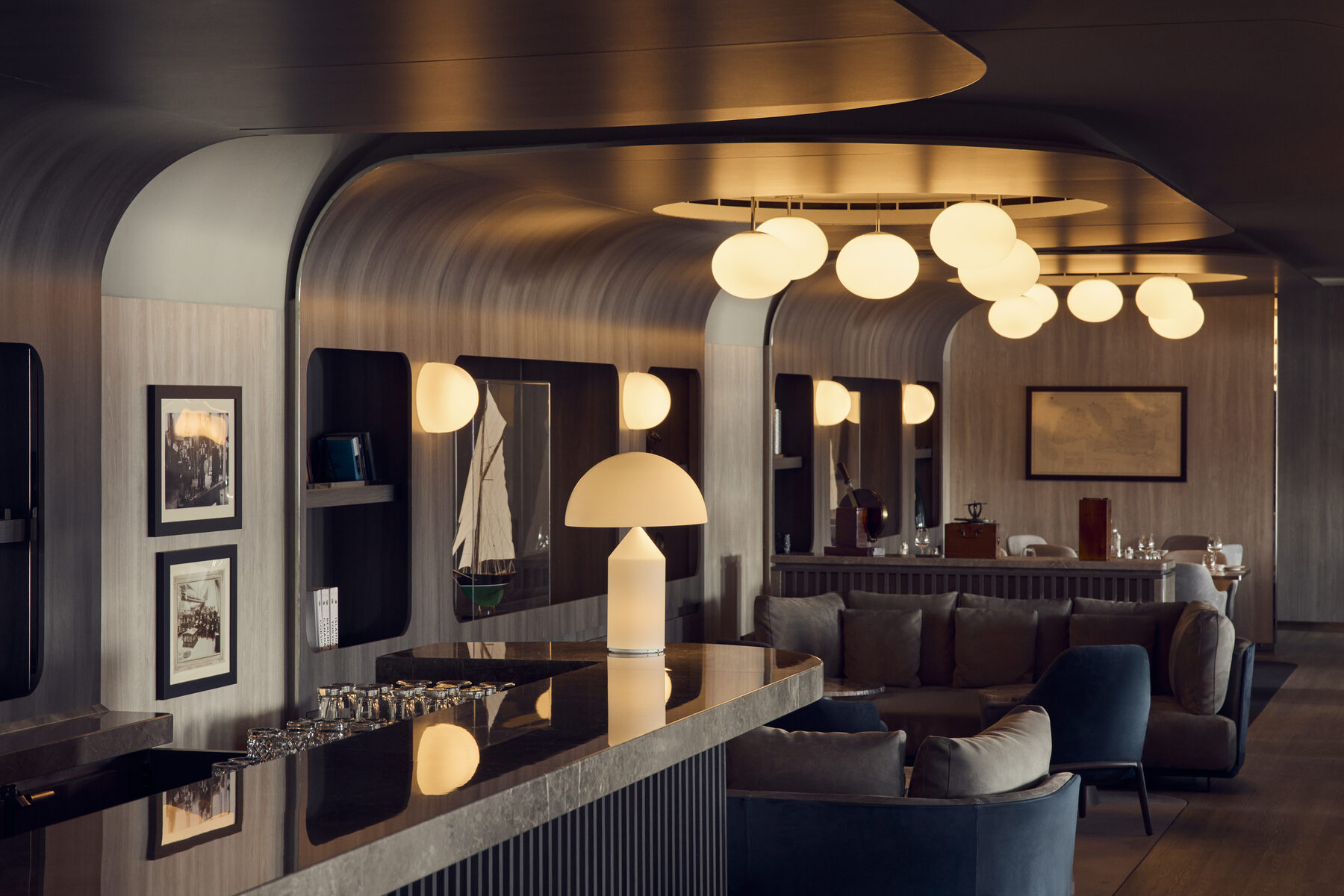 The Med Yacht Club lounge aboard Explora II, a curved bar with globe lights and leather seating