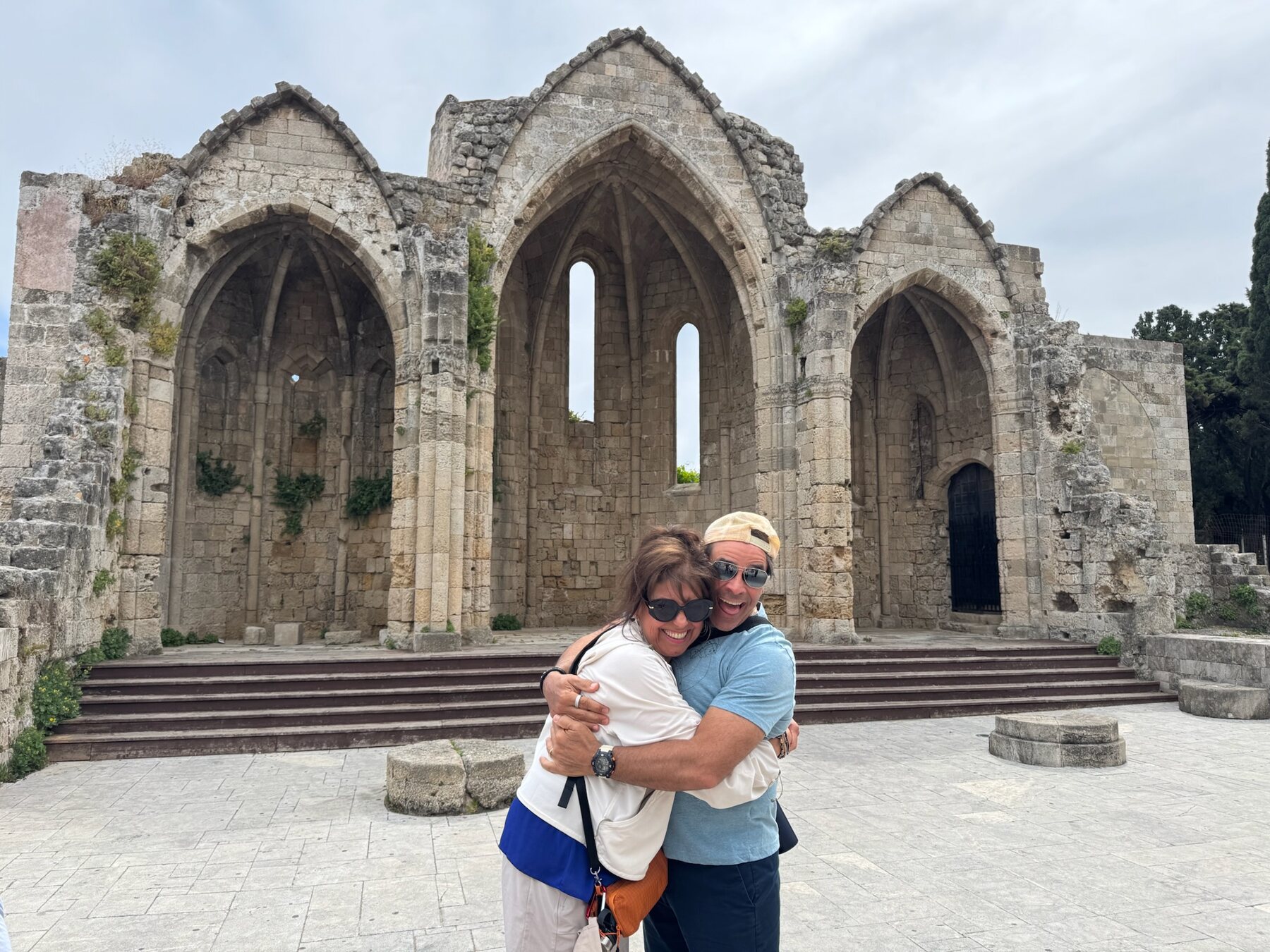 Two of our foodie friends in a joyful hug before the roofless Gothic arches of the ruined Church of Our Lady of the Burgh