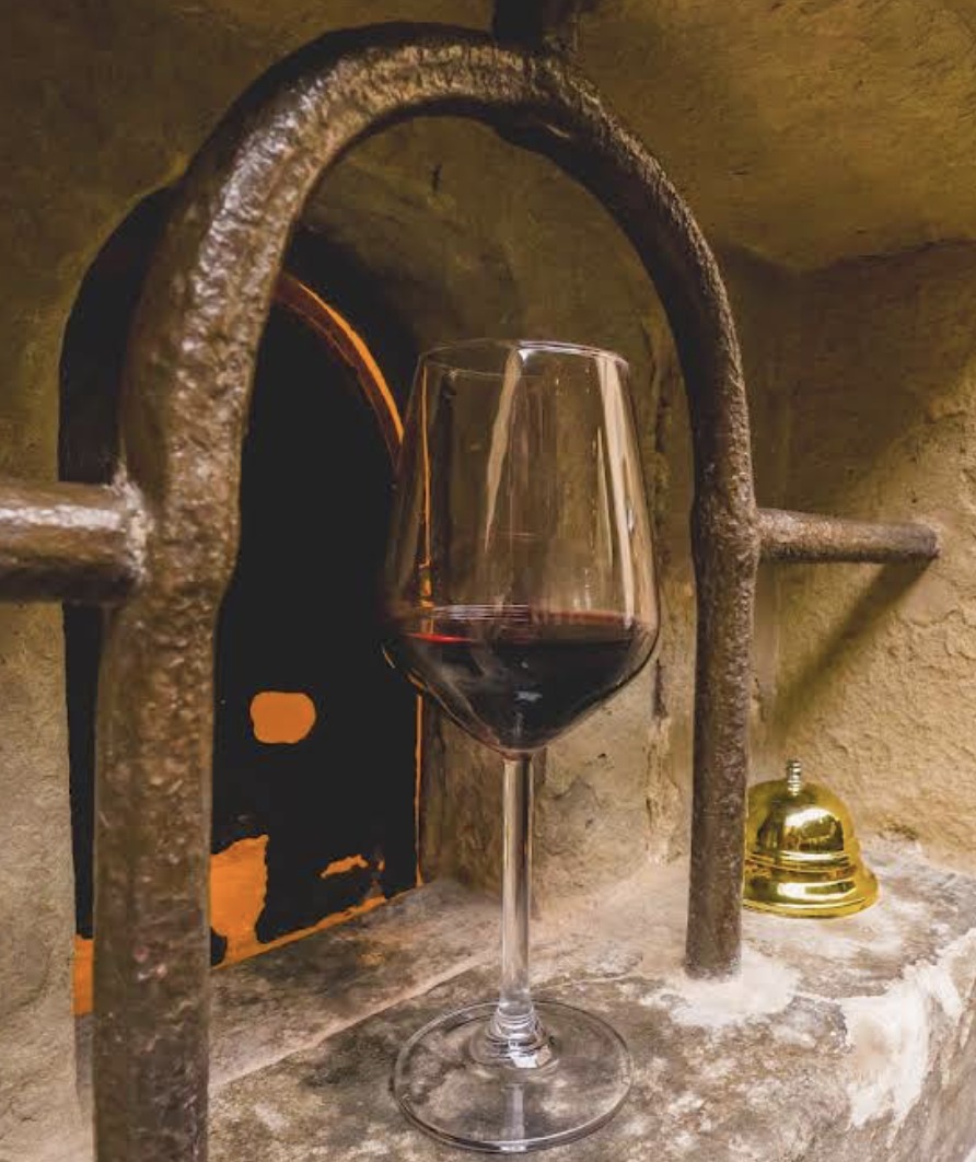 A glass of red wine set in a buchetta del vino, a Florentine wine window