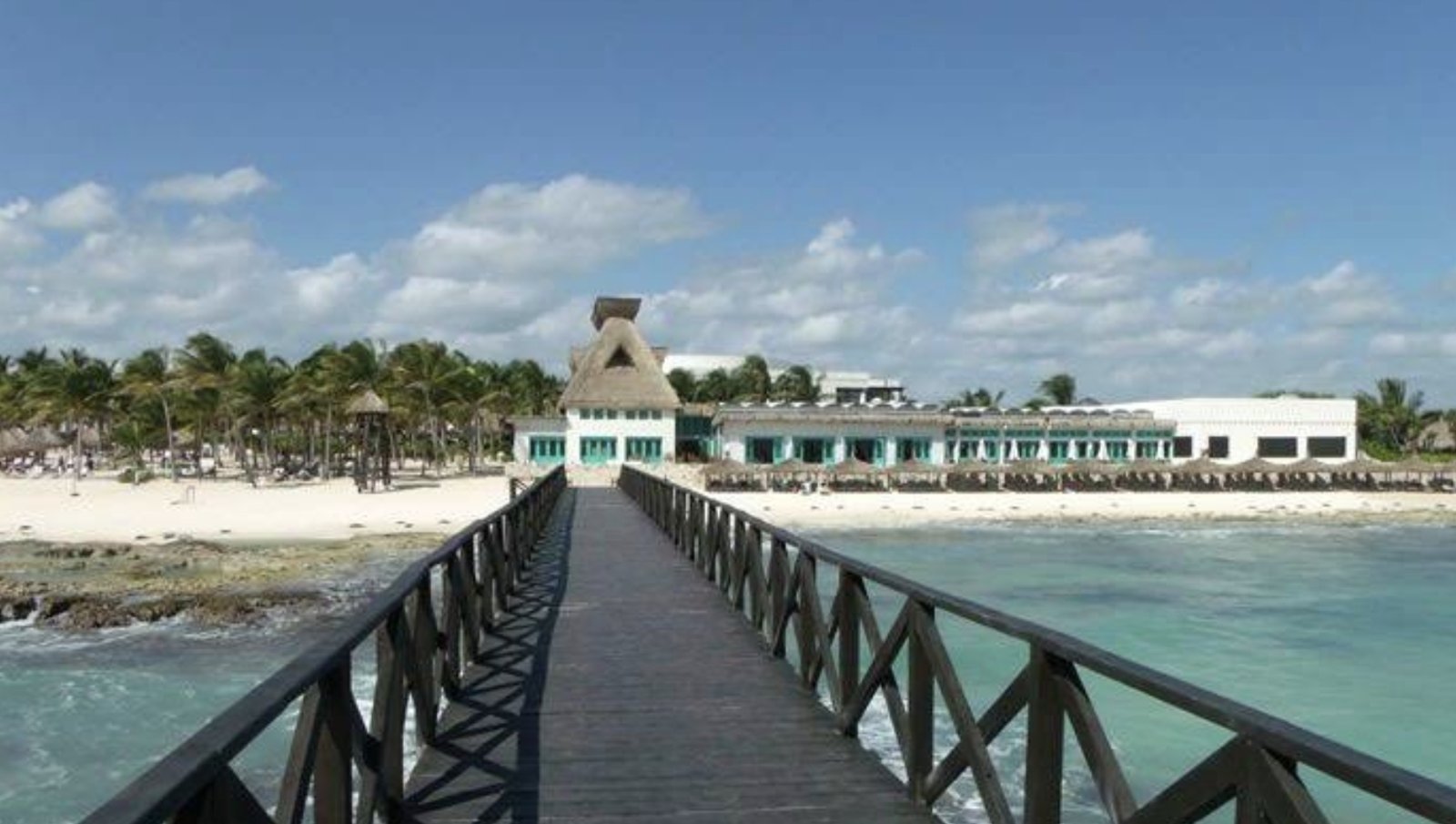 Wooden pier over turquoise water and rocky shoreline at Vidanta Riviera Maya