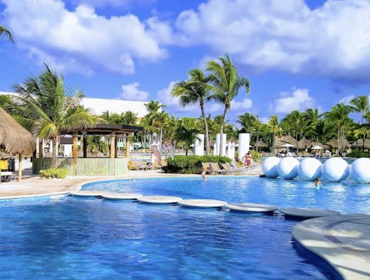 Vidanta main pool with stepping stones, palapas and large white spheres floating at the far edge