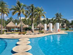 Vidanta main pool with stepping stones, palm trees and palapas