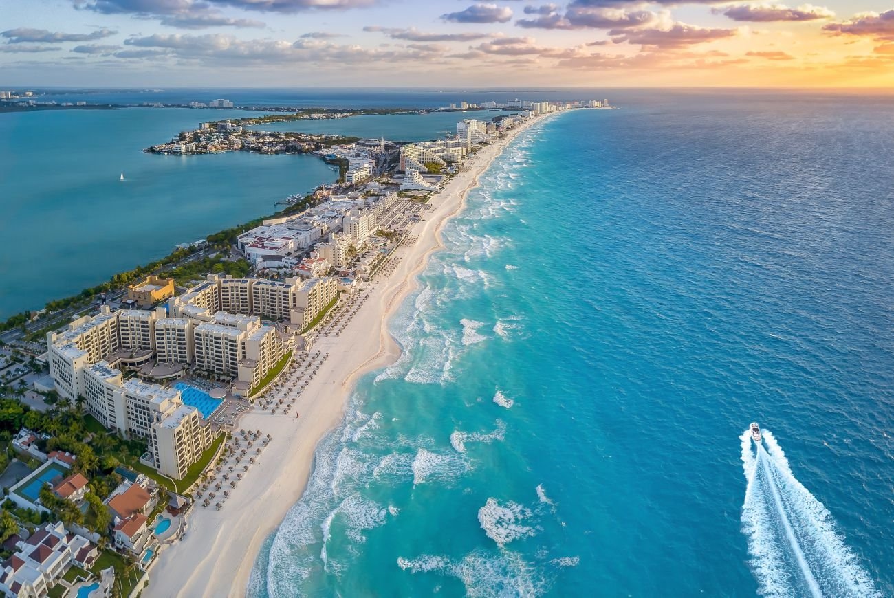Aerial view of the Canc&uacute;n hotel zone with surf rolling onto a long white beach