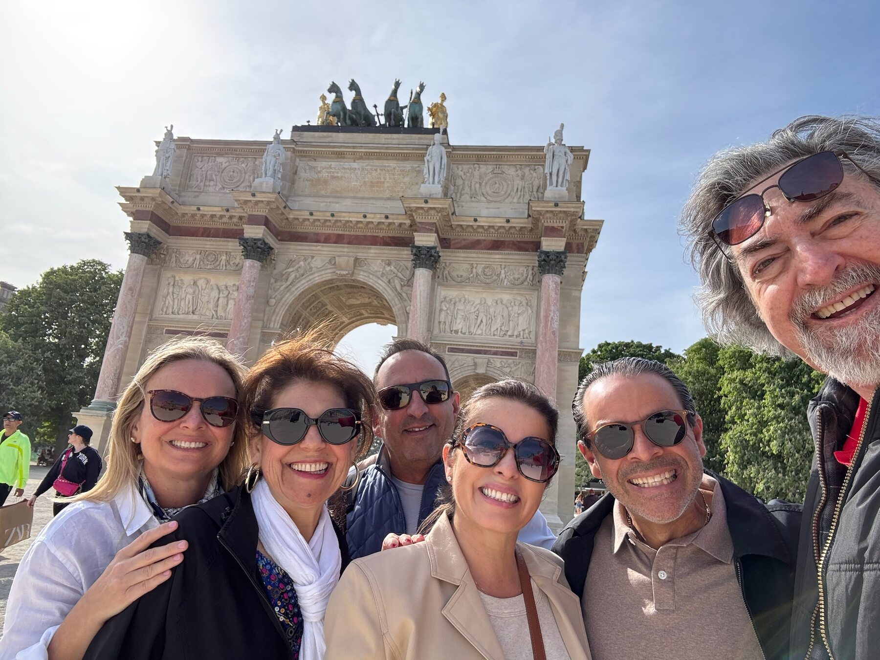 The group of friends smiling in front of the Arc de Triomphe du Carrousel