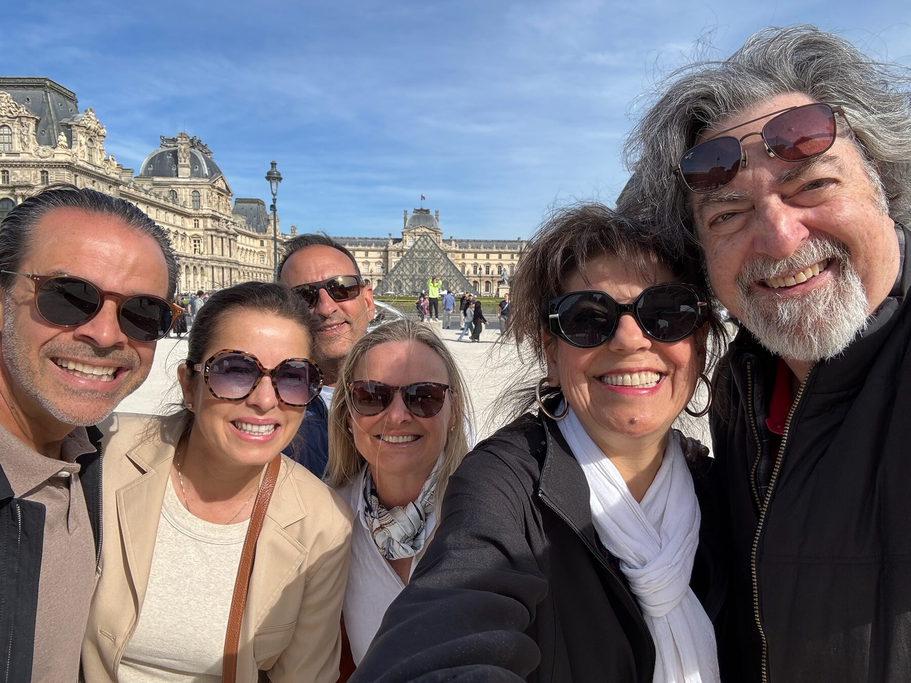 The group posing in the Louvre courtyard with the glass pyramid behind them