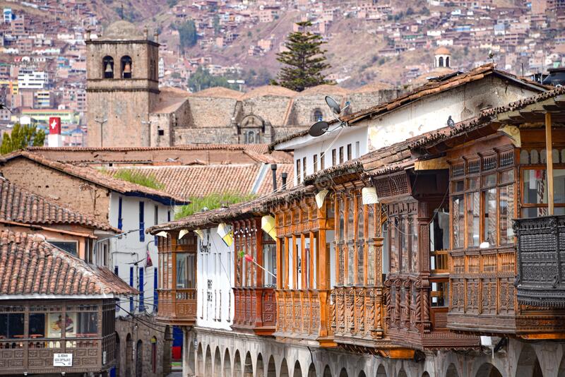 Carved wooden balconies on colonial buildings above a stone arcade