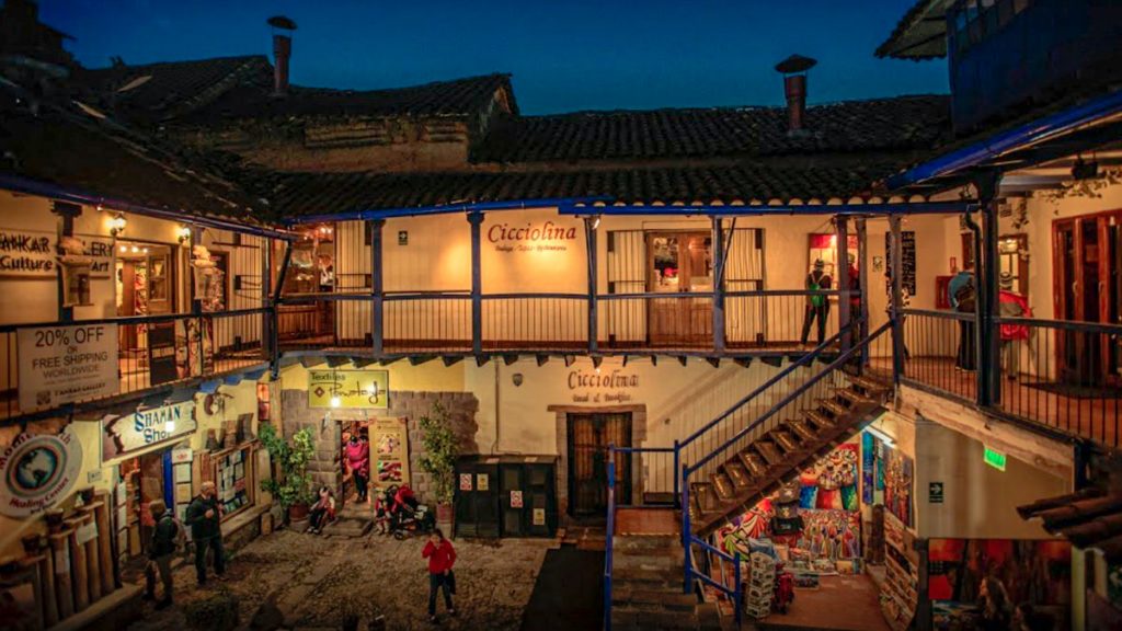 The lit courtyard of Cicciolina at night with a blue balcony and staircase