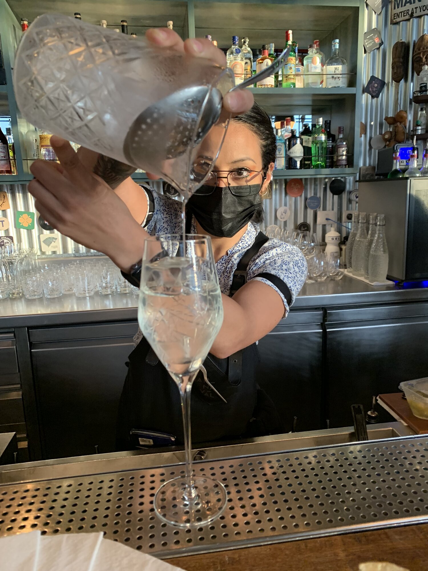 A bartender pouring a drink through a strainer into a tall glass at Carnaval