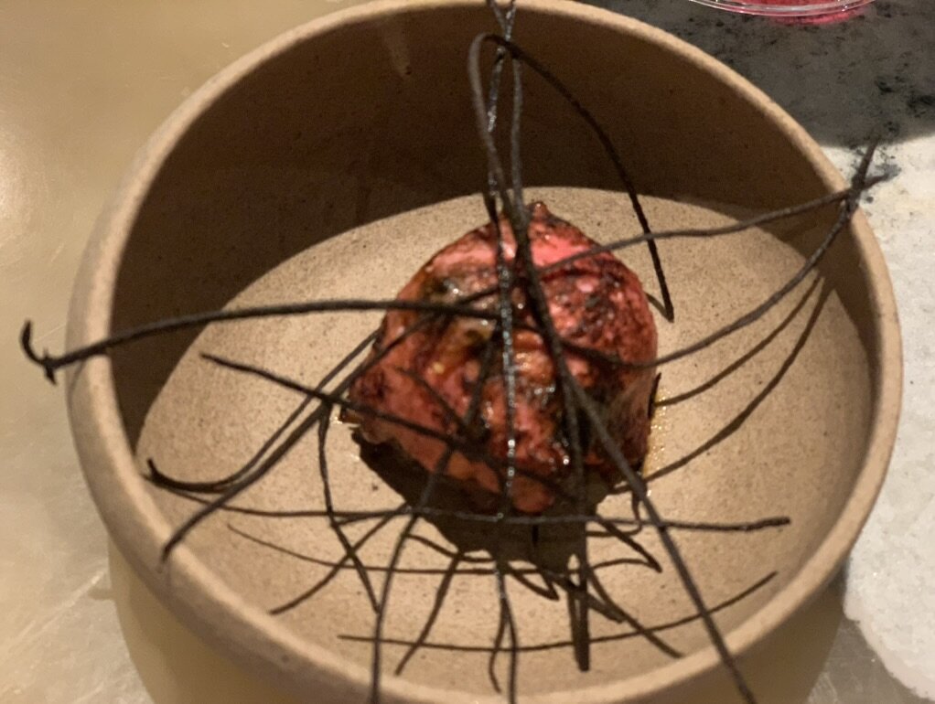 A Central course in a stoneware bowl topped with black strands