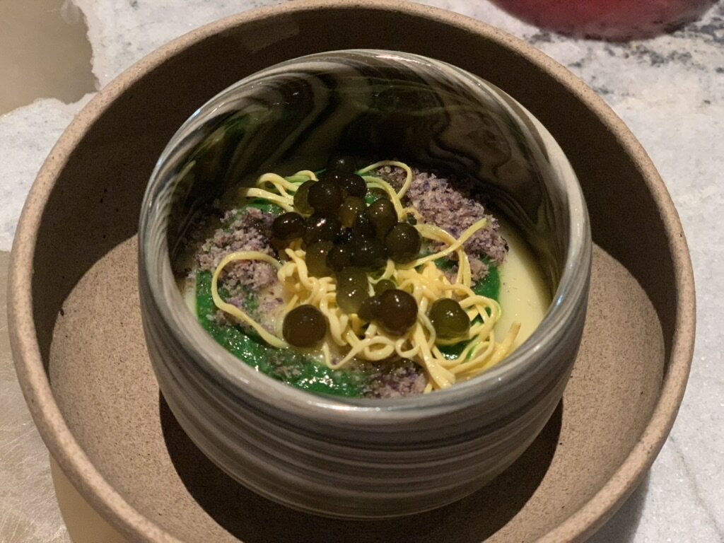 A Central course of noodles and green spheres in a glass bowl