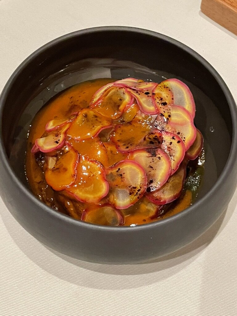 A Central course of thinly sliced radish in an orange sauce