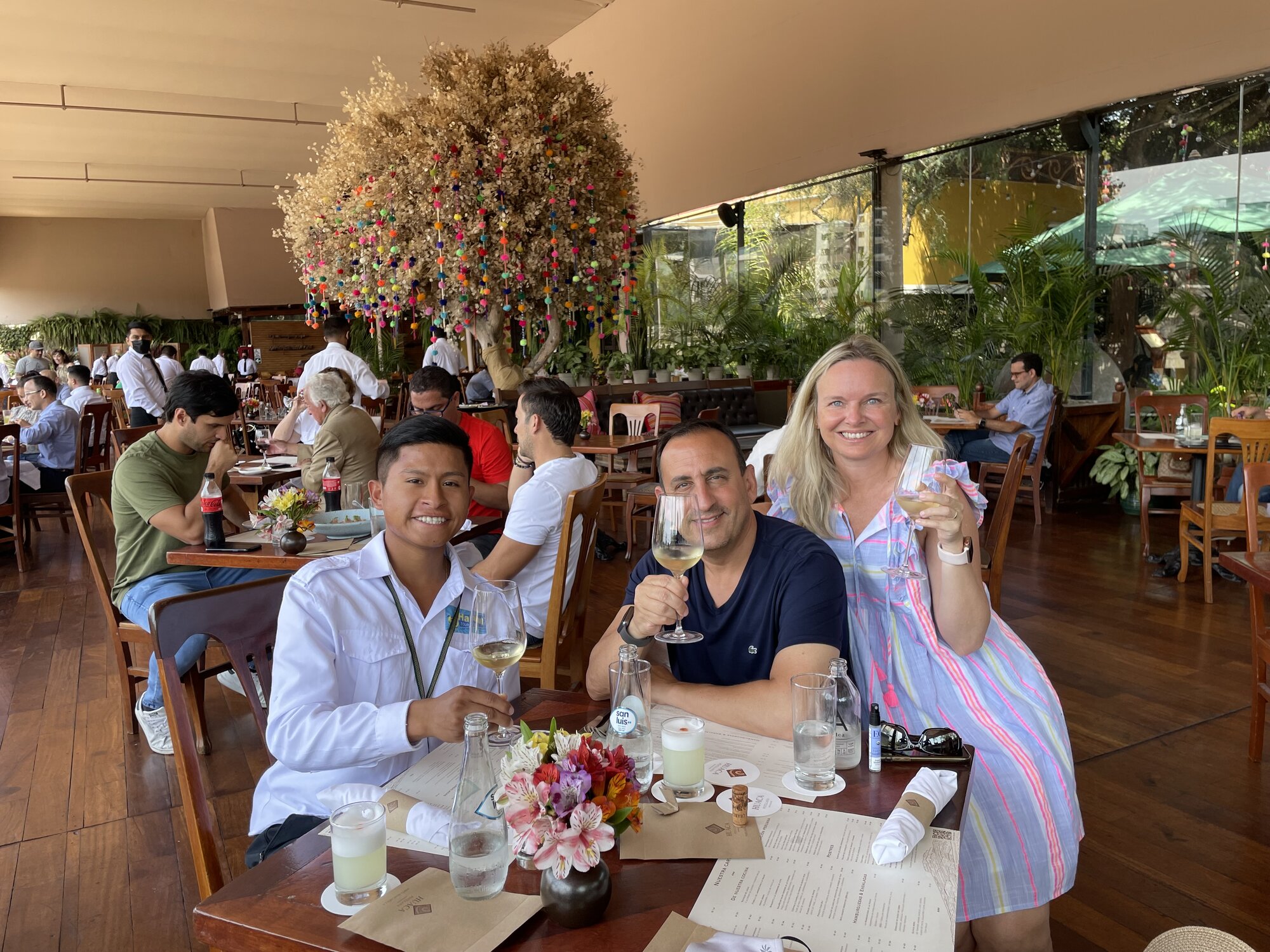 He-Stache, She-Stache and their Haku Tours guide raising glasses at a lunch table inside the Huaca Pucllana restaurant