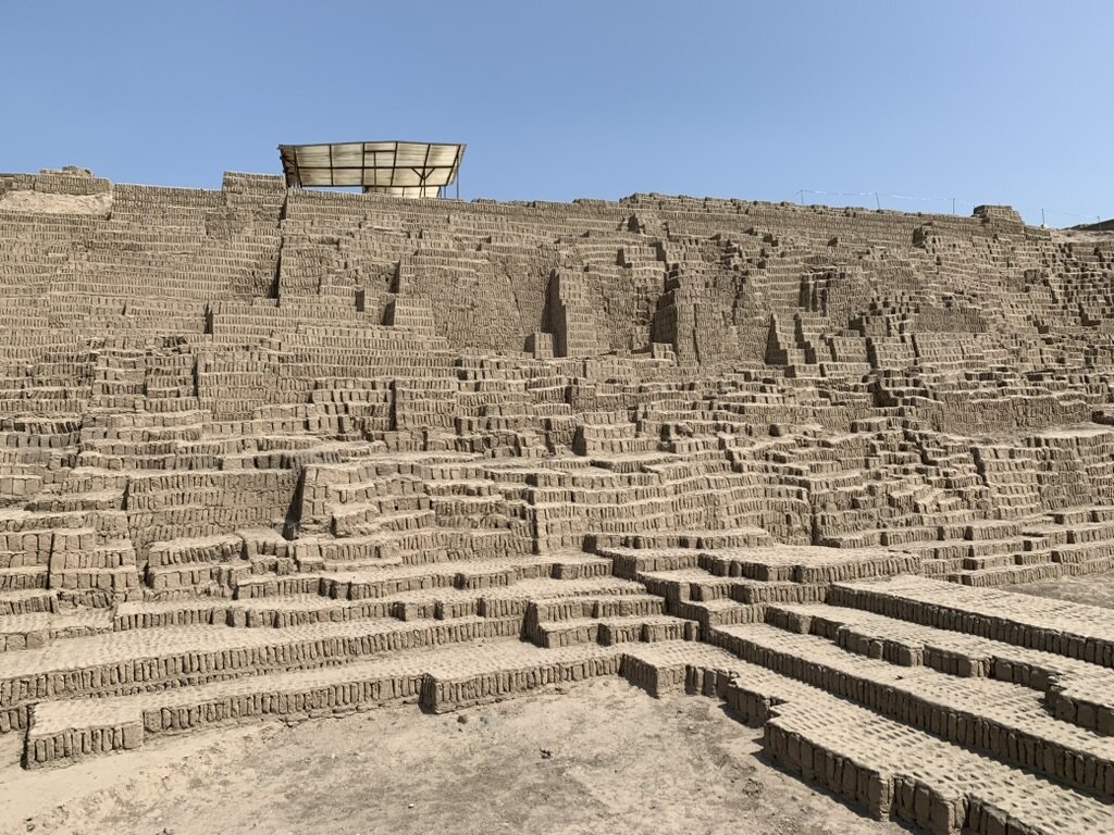 The stepped adobe walls of the Huaca Pucllana pyramid in Miraflores under a blue sky
