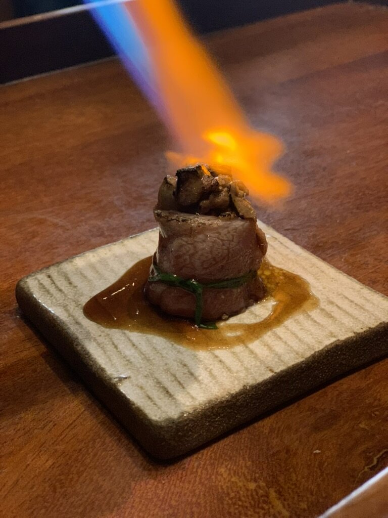 A Maido course being torched with a flame on a ceramic slab