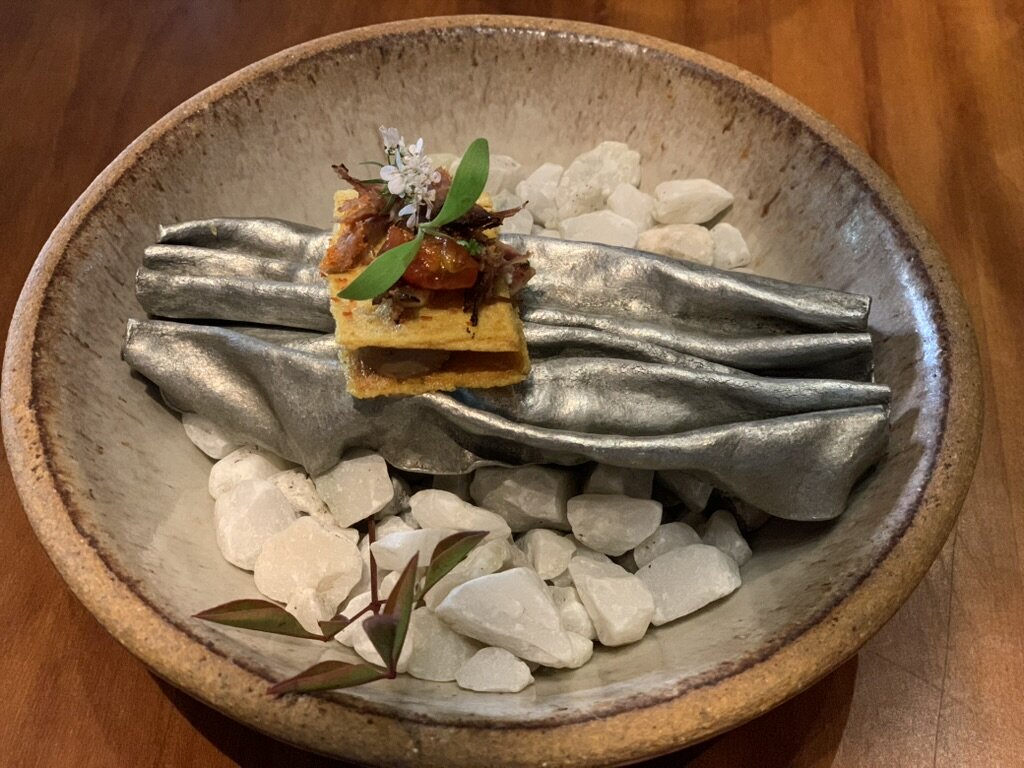 A Maido course plated on a silver folded sheet over white stones