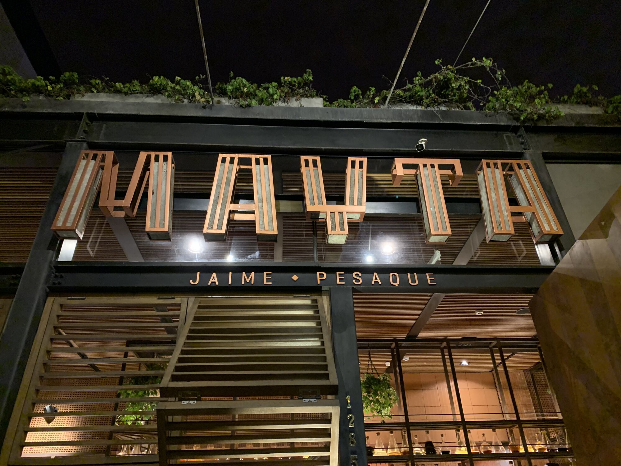 The illuminated Mayta sign above the restaurant entrance in Miraflores at night