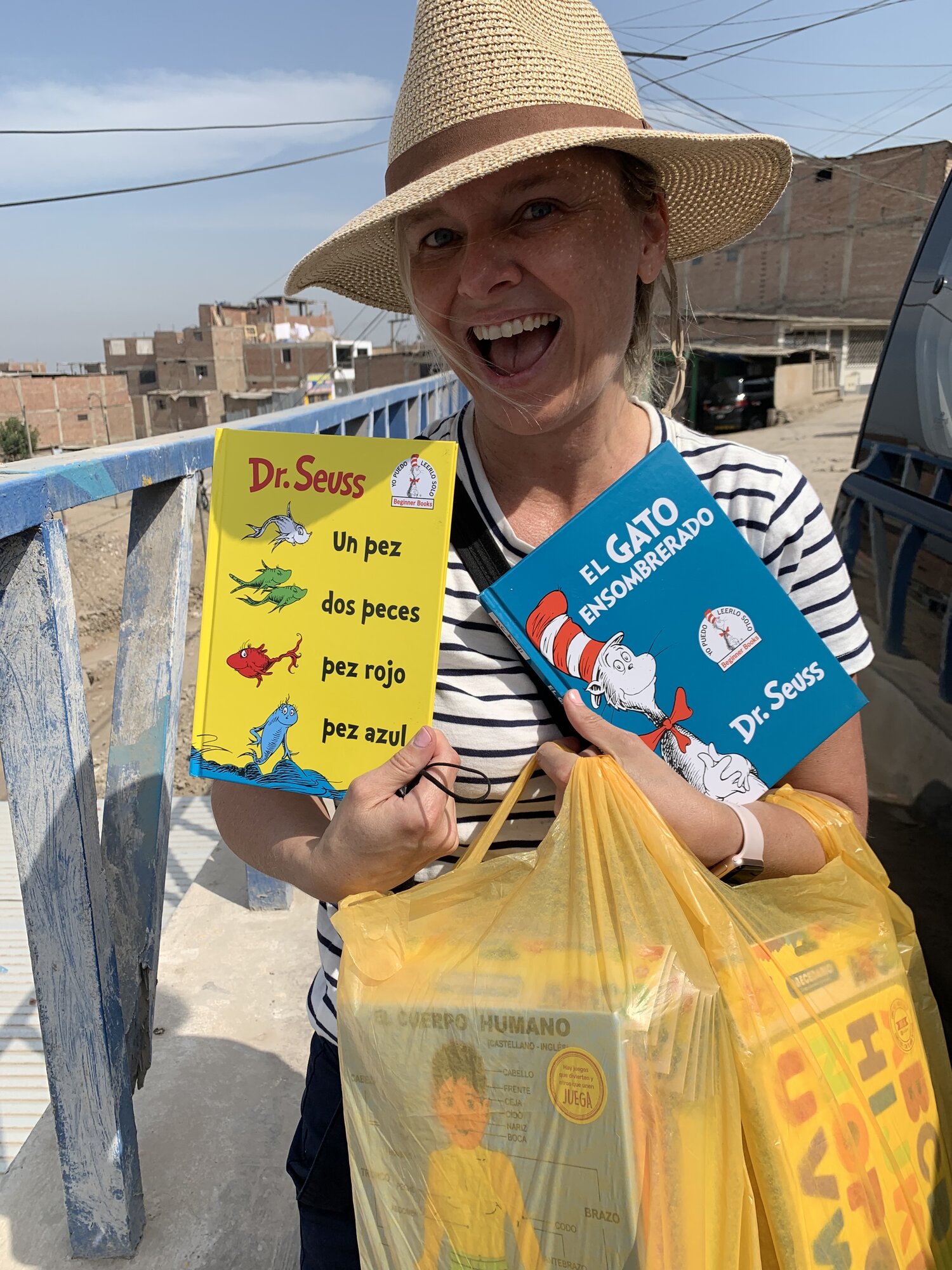 She-Stache holding Spanish-language Dr. Seuss books and a bag of school supplies