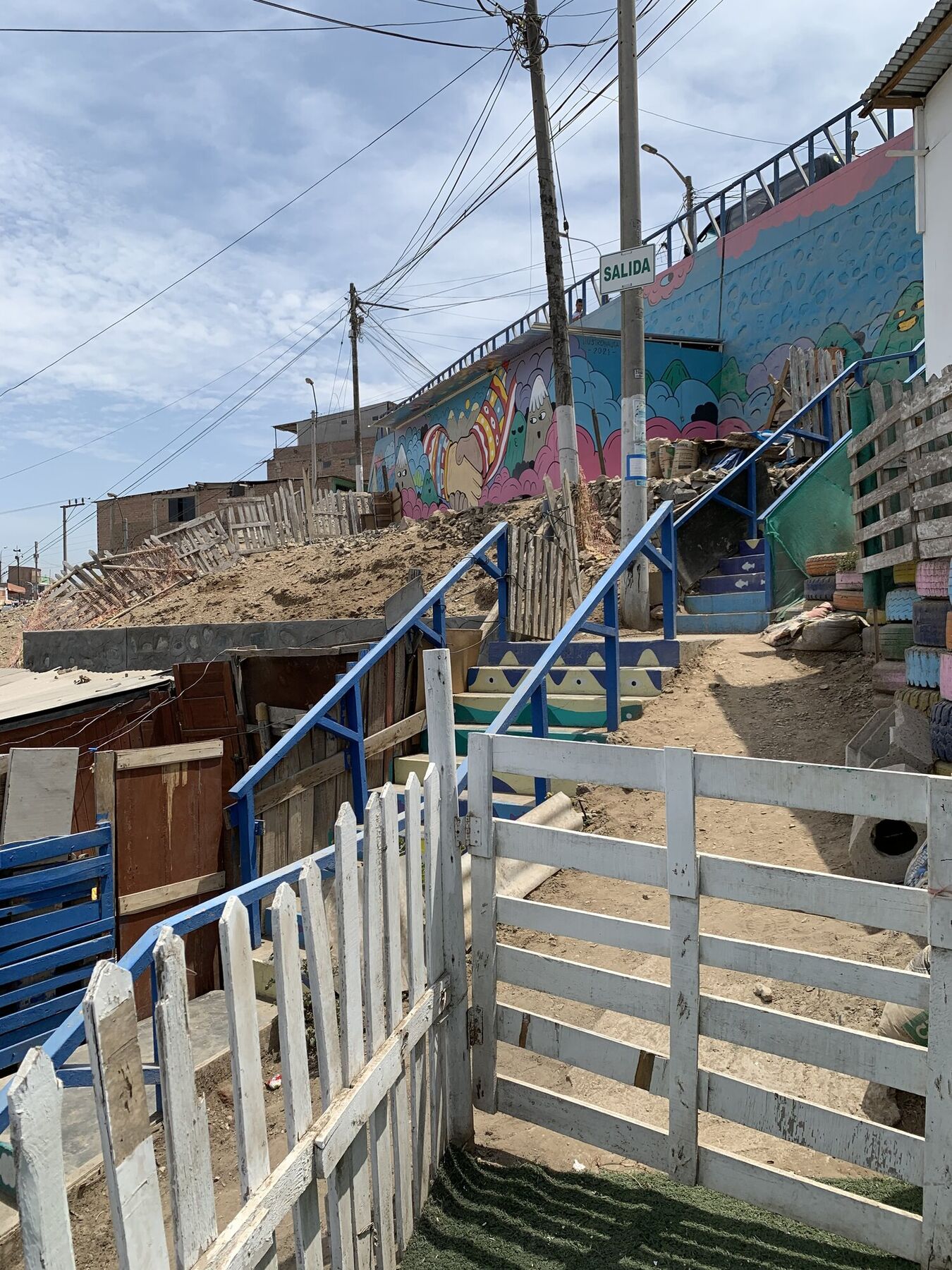 A brightly painted staircase and mural climbing a steep hillside in a Lima pueblo joven