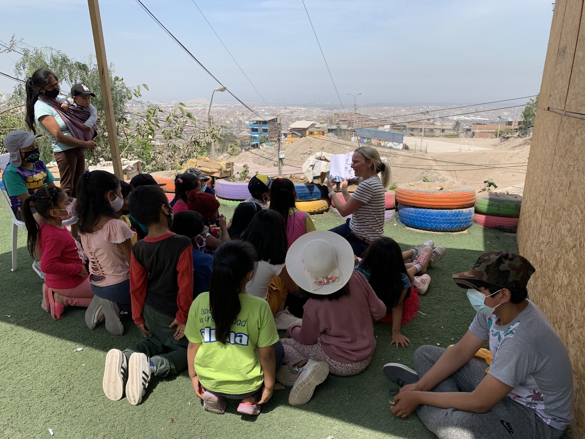 She-Stache reading to a circle of schoolchildren seated on tire seats