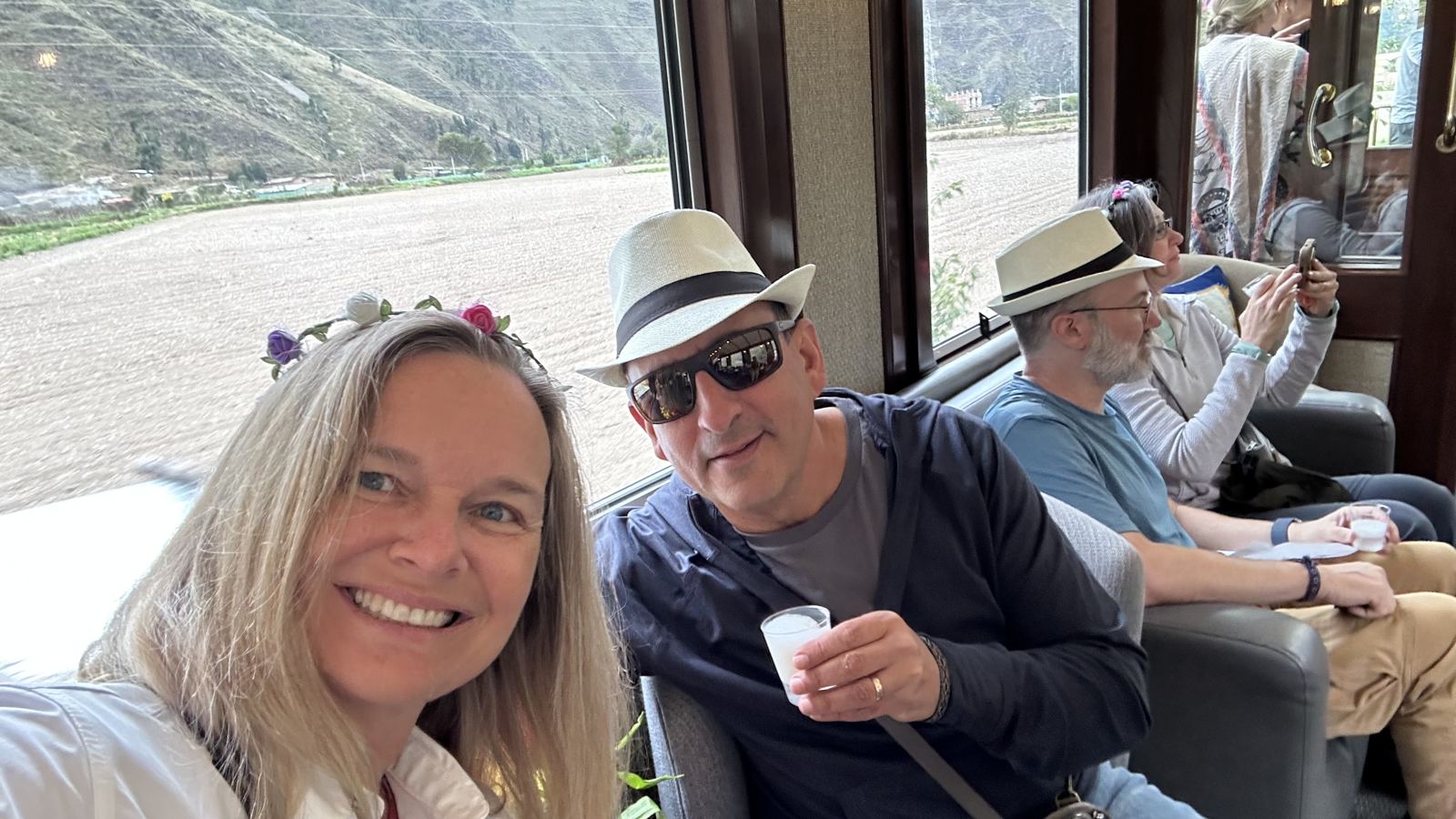 She-Stache and He-Stache on the train, She-Stache holding a small cup of pisco