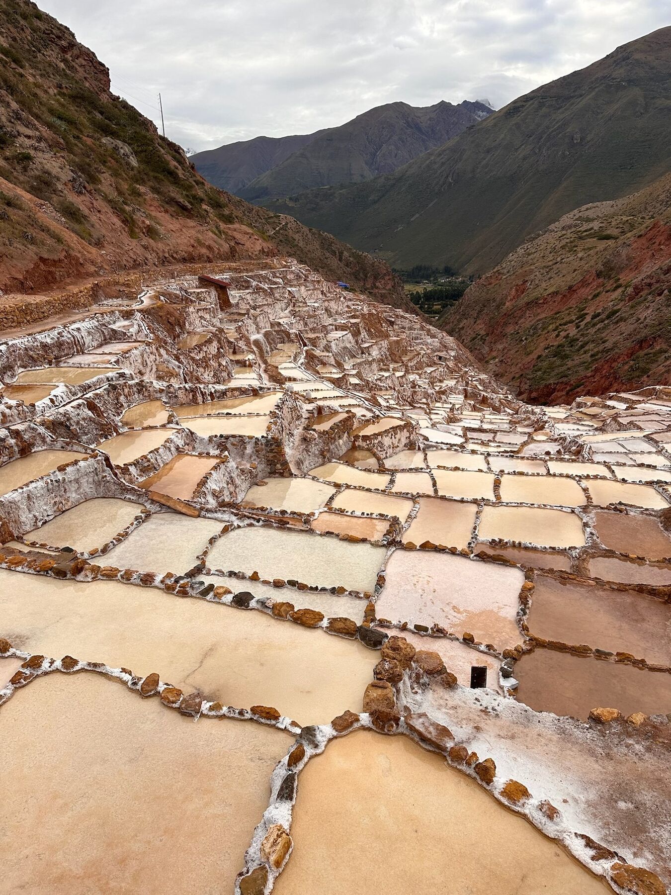 Terraced Inca-era salt pools of Maras in shades of cream and pink, with the valley below