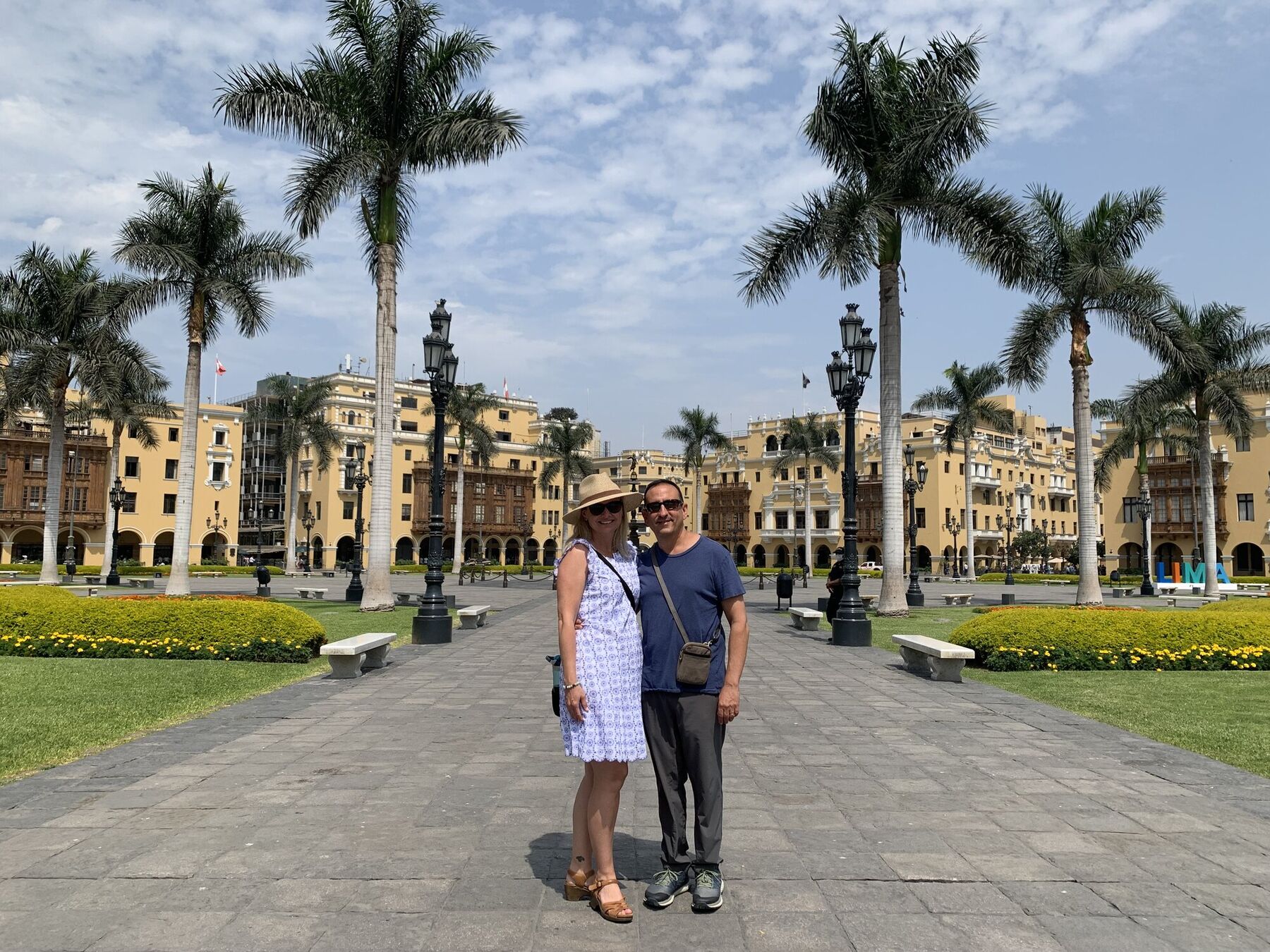 She-Stache and He-Stache walking through Lima's Plaza Mayor beneath the palm trees