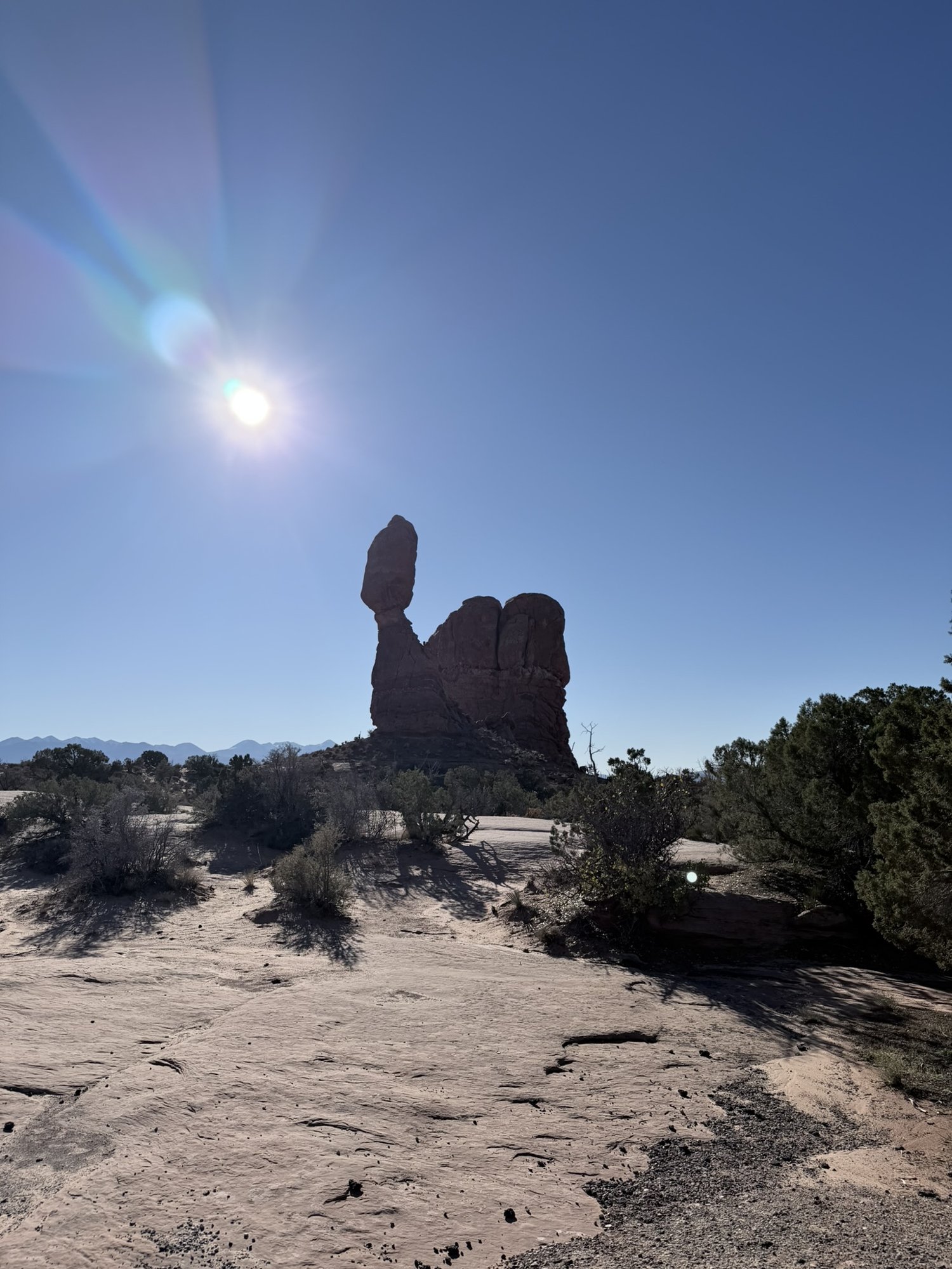 Balanced Rock in Arches National Park silhouetted against a bright morning sun