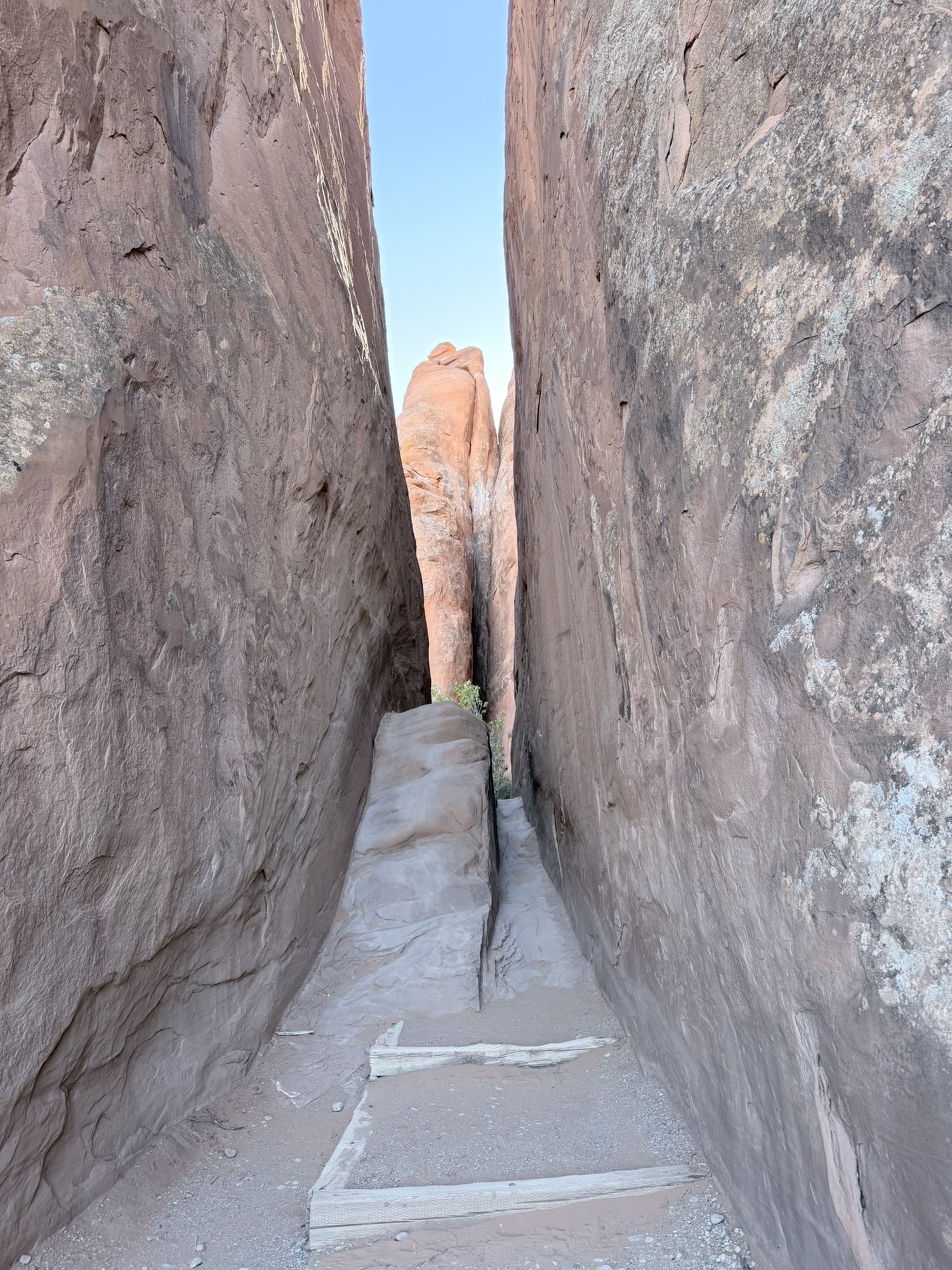 A narrow sandy passage between two towering sandstone fins in Arches National Park