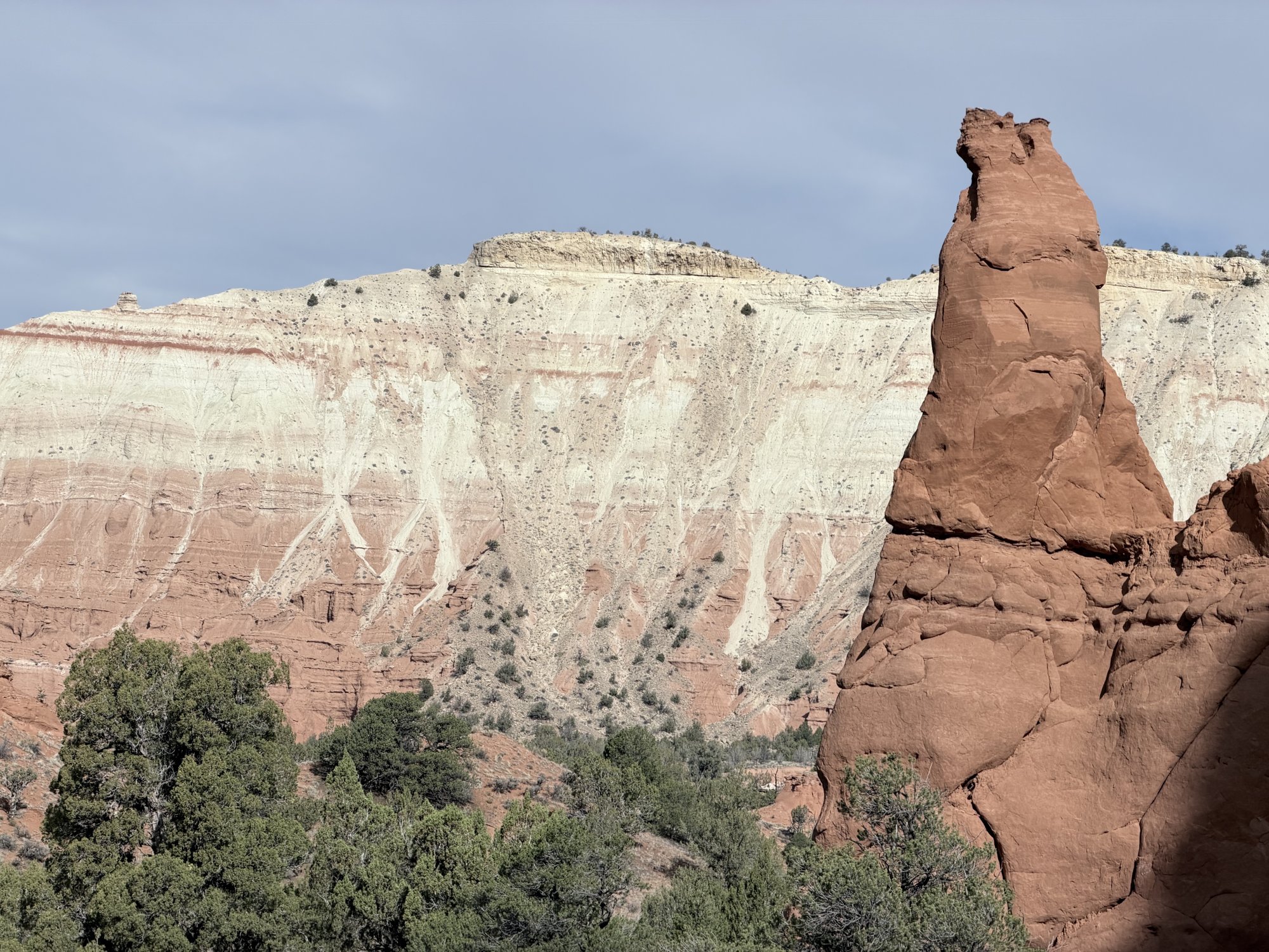 A tall red sandstone spire in front of white-and-red layered cliffs at Kodachrome Basin State Park