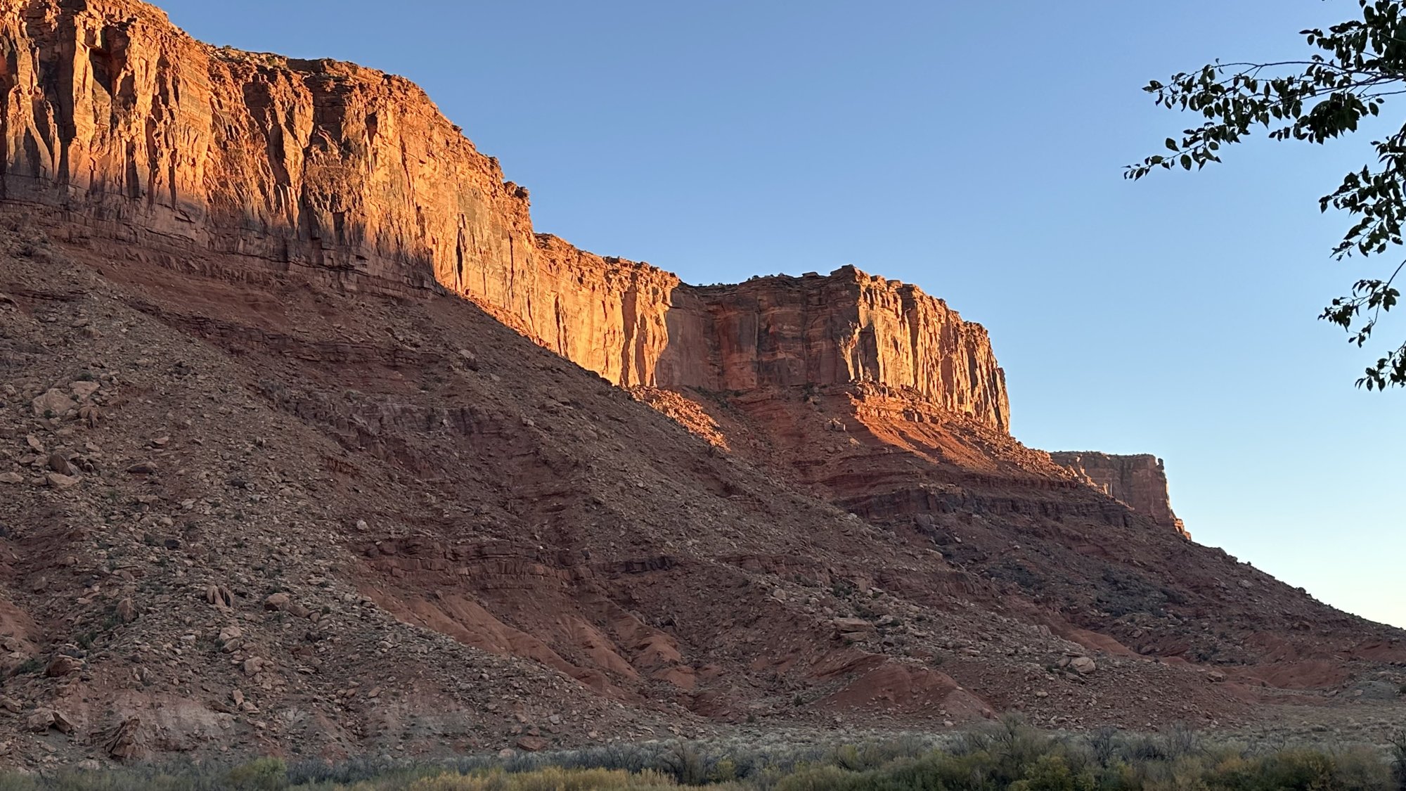 Morning sun lighting up a wall of red sandstone cliffs along UT-128 near Moab